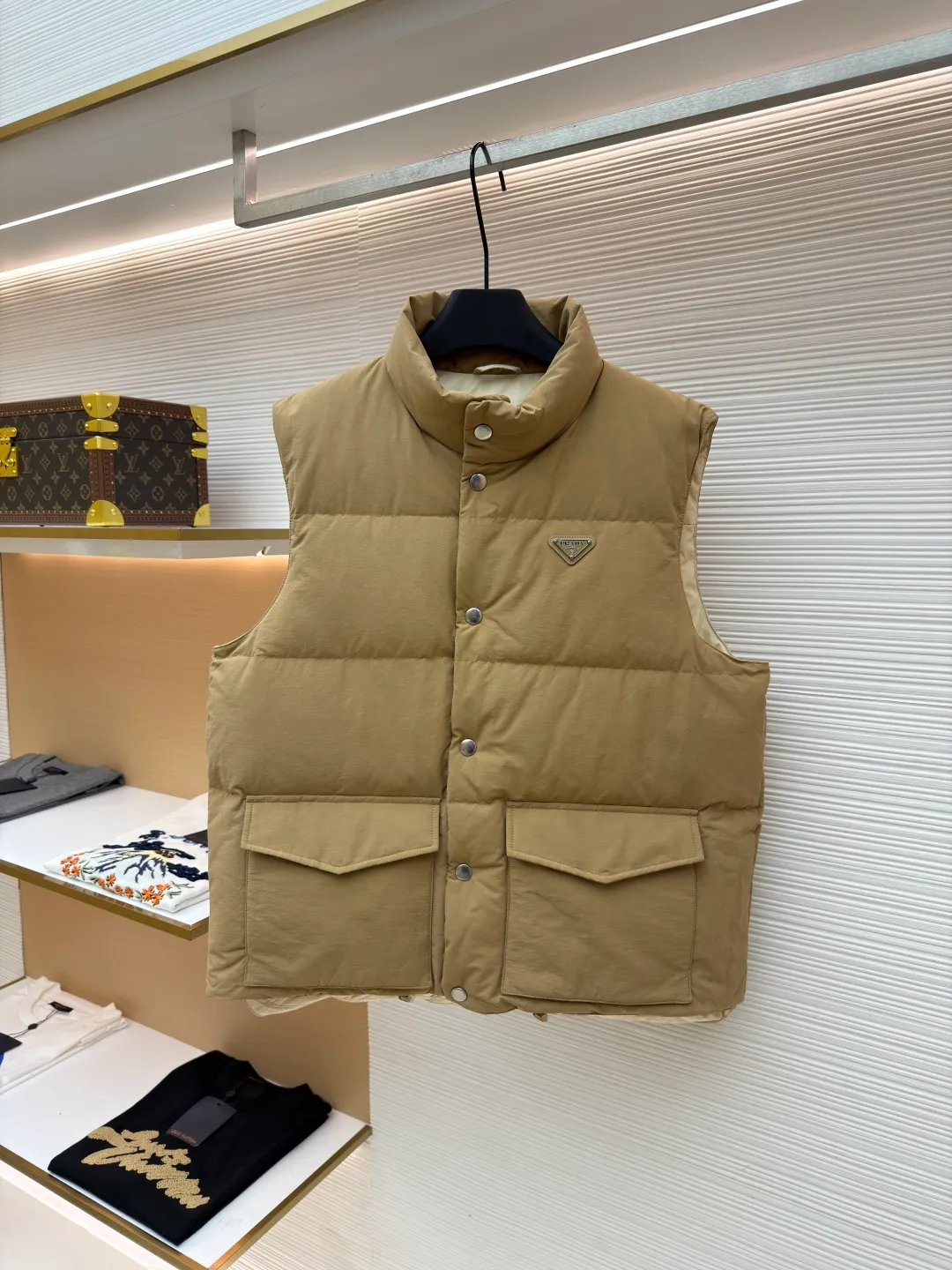 Prada stand collar badge down vest ●Original version: purchased and developed by 18756 ●Item number: 16801377-C30 ●Fabric: white duck down fabric ●Technology: mechanical down filling ●Color: khaki ●Version: Fitted version ●Weight: about 700 grams ●Size: S-M-L-XL ●Description: This vest is made of high-quality water-repellent fabric, and the khaki tone shows the texture. Using three-dimensional quilting technology, the down is evenly divided into full grid-shaped down-filled areas, which not only ensures warmth but also makes the silhouette crisp and three-dimensional. The neckline is designed with a stand-up collar and is matched with a metal snap placket, which is exquisite in texture and easy to put on and take off.  The front chest is decorated with the brand's iconic metal triangle logo, which is highly recognizable; the large patch pockets on both sides are three-dimensionally cut, and the bag mouth is in an inverted trapezoid shape, combining practicality and design. There is a built-in drawstring at the hem, and the tightness can be adjusted freely to suit different wear needs. From fabric selection to detail sewing, every process reflects the brand's strict control of craftsmanship, exquisitely integrating functionality and fashion sense. The overall wiring is straight and delicate, the fabric is comfortable and soft, and the color is consistent without color difference. It can be matched with the same style to create a fashionable look and control various occasions. Customized accessories, complete with three standards, same style for men and women!