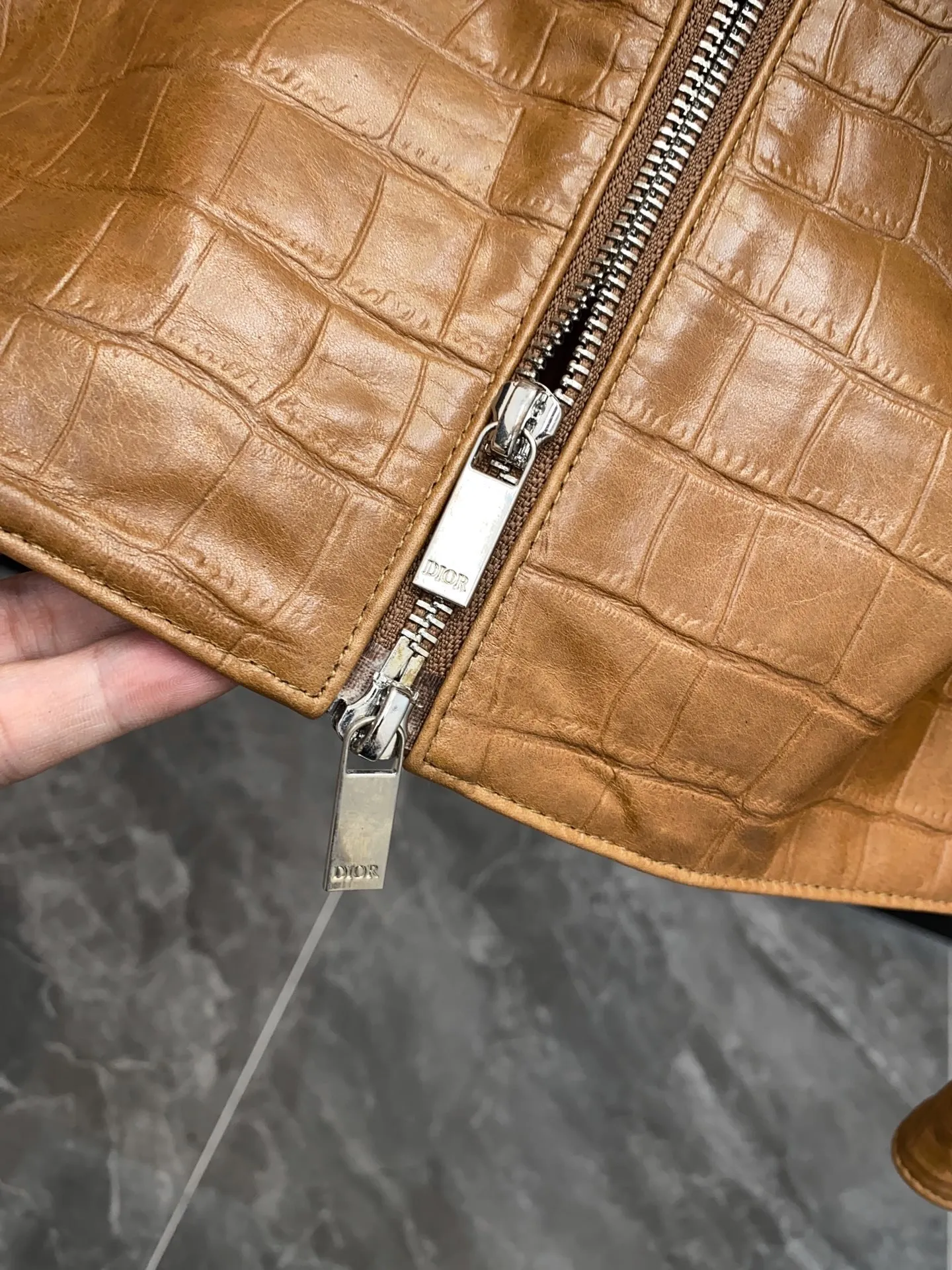 🅿️3060 DIOR Dior's new men's sheepskin jacket for autumn and winter 2025, reshaping autumn and winter style. On the fashion stage, Dior has always been the trend leader. In the autumn and winter of 2025, Dior's new men's sheepskin jacket makes a shocking debut, bringing the ultimate experience to men who pursue quality and style.   The jacket is made of imported brown sheepskin. Its unique color is deep and full of charm, like an elegant poem that has accumulated over time, highlighting the mature and stable temperament of men. This high-quality sheepskin not only looks charming, but also feels soft and delicate. Every time you touch it, you can feel the luxurious texture brought by the top material. It also has good breathability and wear resistance, ensuring that it is comfortable to wear in various occasions.   The design with crocodile print all over the body is the finishing touch. The crocodile pattern symbolizes strength and wildness, injecting unique fashion tension into the jacket, making the wearer stand out from the crowd. Every texture has been carefully suppressed, delicate and clear, showing a lifelike three-dimensional effect, interpreting Dior's persistent pursuit of craftsmanship.   The short version is a precise grasp of modern fashion. It breaks the traditional constraints and cleverly optimizes body proportions. Even men with average figures can instantly have a tall and straight posture when wearing it, showing a neat and capable temperament. Whether it is paired with a simple white T-shirt and jeans for casual daily use, or worn with a shirt and trousers for a business event, it can be perfectly adapted and can easily handle various occasions.   The new products of the season have arrived in the store. We sincerely invite you to try them out and experience the unique charm of Dior's new 2025 autumn and winter men's sheepskin jackets.  Code number: 48-56