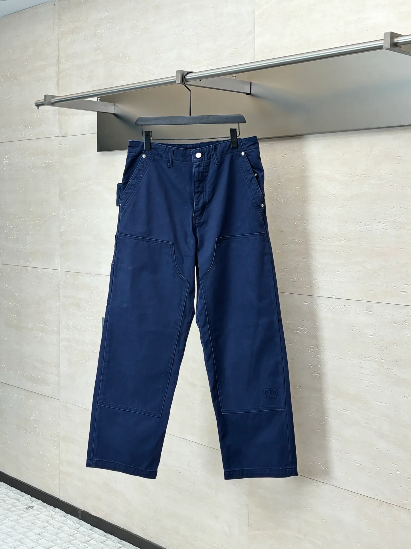 🅿️550 Dio*/Dior 25Fw new workwear blue logging French work pants. Customized twill denim (fixed dyed blue-purple) twill weaving structure. The yarn is customized using long-staple cotton + trace elastic fiber (≤3%) blend. Through the ring spinning + siro spinning composite process, the yarn has high strength and delicate surface. Pre-dyed yarn, cotton yarn is first dip-dyed with indigo 6 times (3-4 times for ordinary jeans) to ensure that the core layer is dyed through. The post-finishing uses nano-scale fixatives to give the blue a deep-sea gradient effect.   The front panel is three-dimensionally spliced, and the five-piece structure of traditional overalls is disassembled into nine asymmetrical pieces. The ergonomic curves are determined through 3D laser scanning. Double-needle differential feeding is used at the seam bone (spacing 2.5mm) to ensure no cracking during stretching.    The back leather is made of calfskin from HAAS leather factory, which is vegetable tanned and hand-rubbed to give it a matte lizard texture. Environmentally friendly dyeing uses water-based dyes, and the edge of the leather label is processed with burnt edge sealing to prevent burrs.    Size: 48/50/52