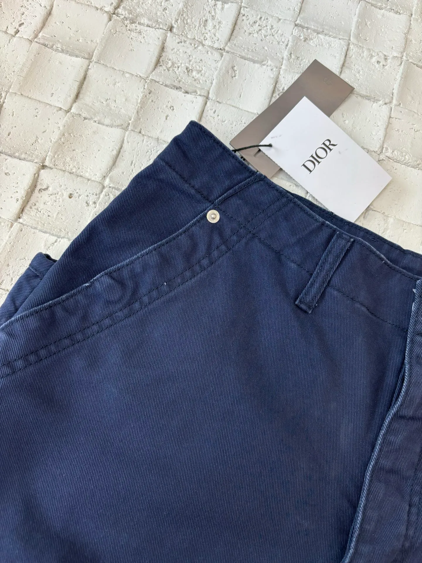 🅿️550 Dio*/Dior 25Fw new workwear blue logging French work pants. Customized twill denim (fixed dyed blue-purple) twill weaving structure. The yarn is customized using long-staple cotton + trace elastic fiber (≤3%) blend. Through the ring spinning + siro spinning composite process, the yarn has high strength and delicate surface. Pre-dyed yarn, cotton yarn is first dip-dyed with indigo 6 times (3-4 times for ordinary jeans) to ensure that the core layer is dyed through. The post-finishing uses nano-scale fixatives to give the blue a deep-sea gradient effect.   The front panel is three-dimensionally spliced, and the five-piece structure of traditional overalls is disassembled into nine asymmetrical pieces. The ergonomic curves are determined through 3D laser scanning. Double-needle differential feeding is used at the seam bone (spacing 2.5mm) to ensure no cracking during stretching.    The back leather is made of calfskin from HAAS leather factory, which is vegetable tanned and hand-rubbed to give it a matte lizard texture. Environmentally friendly dyeing uses water-based dyes, and the edge of the leather label is processed with burnt edge sealing to prevent burrs.    Size: 48/50/52
