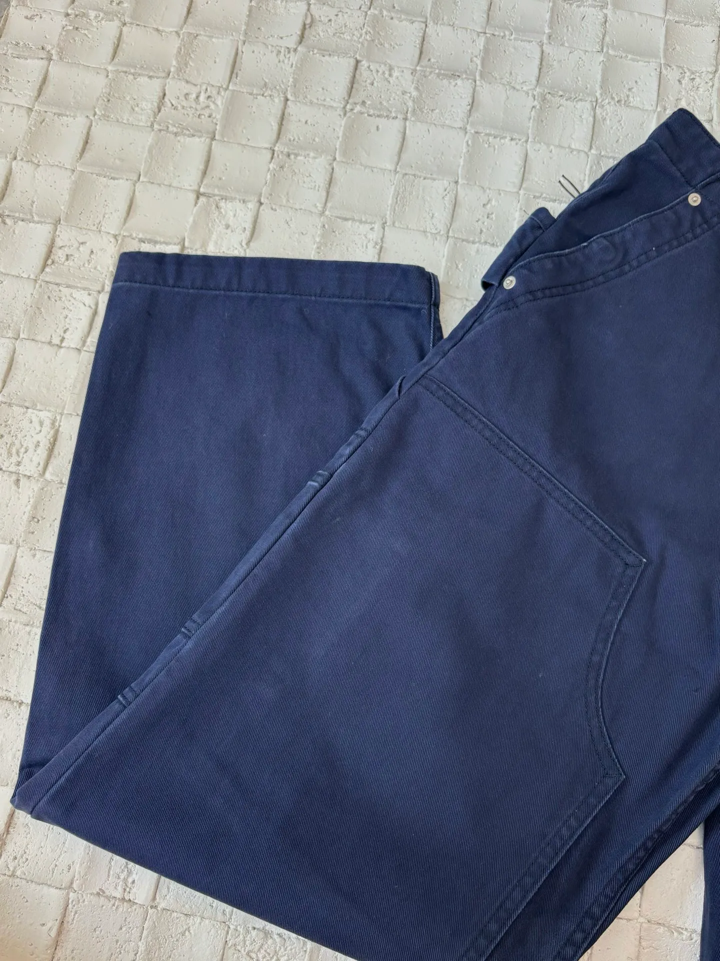🅿️550 Dio*/Dior 25Fw new workwear blue logging French work pants. Customized twill denim (fixed dyed blue-purple) twill weaving structure. The yarn is customized using long-staple cotton + trace elastic fiber (≤3%) blend. Through the ring spinning + siro spinning composite process, the yarn has high strength and delicate surface. Pre-dyed yarn, cotton yarn is first dip-dyed with indigo 6 times (3-4 times for ordinary jeans) to ensure that the core layer is dyed through. The post-finishing uses nano-scale fixatives to give the blue a deep-sea gradient effect.   The front panel is three-dimensionally spliced, and the five-piece structure of traditional overalls is disassembled into nine asymmetrical pieces. The ergonomic curves are determined through 3D laser scanning. Double-needle differential feeding is used at the seam bone (spacing 2.5mm) to ensure no cracking during stretching.    The back leather is made of calfskin from HAAS leather factory, which is vegetable tanned and hand-rubbed to give it a matte lizard texture. Environmentally friendly dyeing uses water-based dyes, and the edge of the leather label is processed with burnt edge sealing to prevent burrs.    Size: 48/50/52