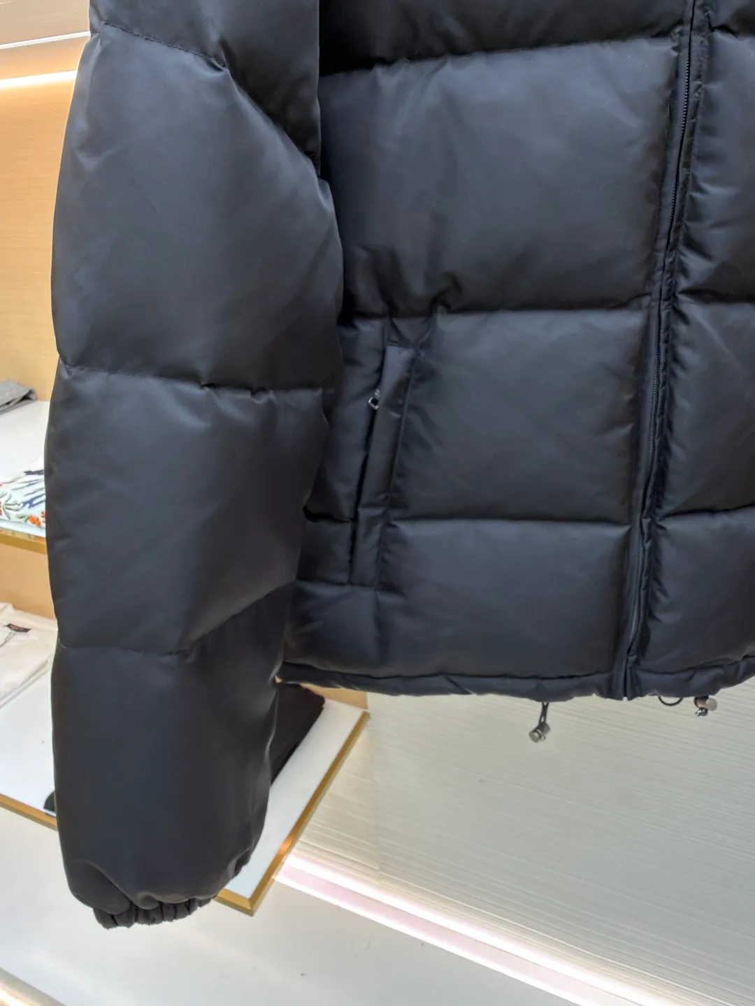 Prada nylon triangle down jacket ●Original version: Purchased and developed by 13557 ●Item number: 1681282-C95 ●Fabric: white duck down fabric ●Technology: mechanical down filling ●Color: black ●Version: fitted version ●Weight: about 1025 grams ●Size: S-M-L-XL ●Description: Made of high-count and high-density nylon woven fabric, it is a lightweight, strong and fine-textured advanced fabric. Its physical complexity lies in the fact that while achieving extreme lightweight, it provides excellent tear resistance and abrasion resistance through a dense fabric structure, solving the industry problem of light weight and durability that are often contradictory. Waterproof coating: This is not a simple film, but a microscopic functional polymer layer coated on the surface of the fabric after it is woven. Its complexity is reflected in its chemical properties: it can effectively reduce the surface tension of the fabric, making it impossible for water droplets to penetrate its fiber gaps, thereby forming a lotus leaf effect and achieving efficient waterproofing. At the same time, this coating usually has a certain degree of breathability, allowing moisture emitted by the body to escape and maintaining a comfortable internal microclimate. This is a precise balancing technology. The laser-burned triangle mark on the chest is the pinnacle of the complexity of the entire garment's craftsmanship. Laser burning is a non-contact precision processing technology. Using a laser beam of specific wavelength and energy, the fibers on the surface of the fabric are vaporized according to a preset digital path. The laser can accurately "carve" every detail of the logo without damaging the underlying fabric structure, with clear and sharp edges and a unique, slightly burning matte texture. This is completely different from traditional embroidery or offset printing. It is integrated with the fabric itself and cannot be peeled off. It also requires extremely high stability in process control - if the energy is slightly weaker, the pattern will be unclear, and if the energy is slightly stronger, it may penetrate the fabric. The core is filled with 90% pure white duck down. "90% pure white duck down" is an indicator that has been strictly sorted. The thermal insulation principle of down is that its three-dimensional velvet can hold a large amount of still air and form an efficient thermal insulation layer. To sum up, every part of this down jacket goes beyond basic functions and embodies full-link innovation and quality control from raw material selection, textile engineering, chemical processing to digital finishing. The overall wiring is straight and delicate, the fabric is comfortable and soft, and the color is consistent without color difference. It can be matched with the same style to create a fashionable look and control various occasions. Customized accessories, complete with three standards, same style for men and women!