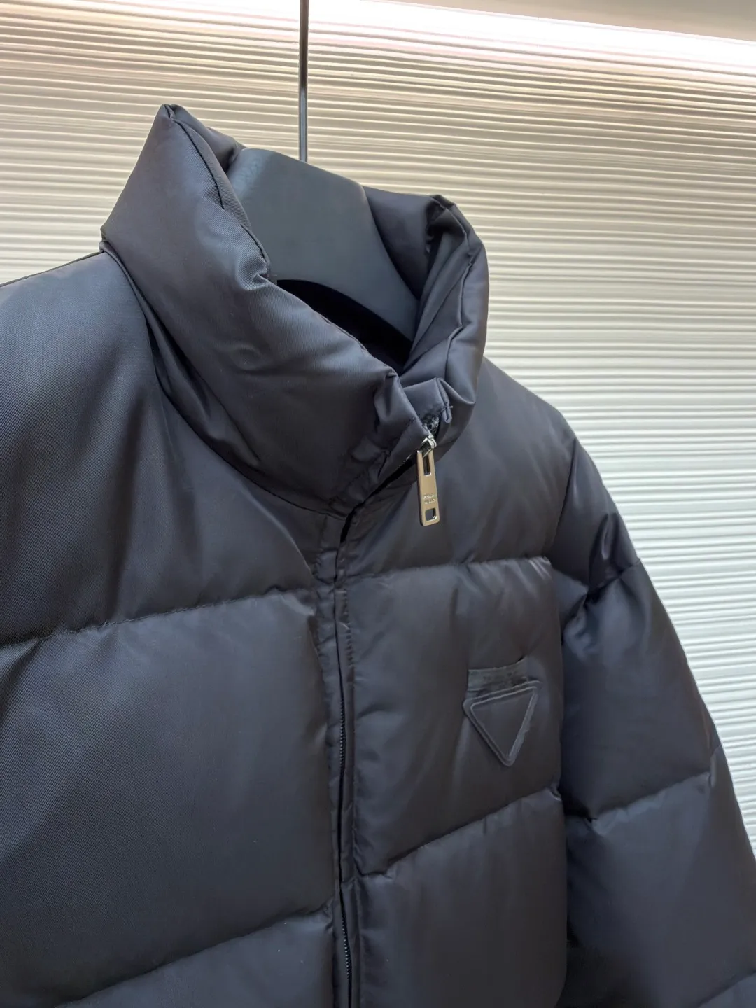 Prada nylon triangle down jacket ●Original version: Purchased and developed by 13557 ●Item number: 1681282-C95 ●Fabric: white duck down fabric ●Technology: mechanical down filling ●Color: black ●Version: fitted version ●Weight: about 1025 grams ●Size: S-M-L-XL ●Description: Made of high-count and high-density nylon woven fabric, it is a lightweight, strong and fine-textured advanced fabric. Its physical complexity lies in the fact that while achieving extreme lightweight, it provides excellent tear resistance and abrasion resistance through a dense fabric structure, solving the industry problem of light weight and durability that are often contradictory. Waterproof coating: This is not a simple film, but a microscopic functional polymer layer coated on the surface of the fabric after it is woven. Its complexity is reflected in its chemical properties: it can effectively reduce the surface tension of the fabric, making it impossible for water droplets to penetrate its fiber gaps, thereby forming a lotus leaf effect and achieving efficient waterproofing. At the same time, this coating usually has a certain degree of breathability, allowing moisture emitted by the body to escape and maintaining a comfortable internal microclimate. This is a precise balancing technology. The laser-burned triangle mark on the chest is the pinnacle of the complexity of the entire garment's craftsmanship. Laser burning is a non-contact precision processing technology. Using a laser beam of specific wavelength and energy, the fibers on the surface of the fabric are vaporized according to a preset digital path. The laser can accurately "carve" every detail of the logo without damaging the underlying fabric structure, with clear and sharp edges and a unique, slightly burning matte texture. This is completely different from traditional embroidery or offset printing. It is integrated with the fabric itself and cannot be peeled off. It also requires extremely high stability in process control - if the energy is slightly weaker, the pattern will be unclear, and if the energy is slightly stronger, it may penetrate the fabric. The core is filled with 90% pure white duck down. "90% pure white duck down" is an indicator that has been strictly sorted. The thermal insulation principle of down is that its three-dimensional velvet can hold a large amount of still air and form an efficient thermal insulation layer. To sum up, every part of this down jacket goes beyond basic functions and embodies full-link innovation and quality control from raw material selection, textile engineering, chemical processing to digital finishing. The overall wiring is straight and delicate, the fabric is comfortable and soft, and the color is consistent without color difference. It can be matched with the same style to create a fashionable look and control various occasions. Customized accessories, complete with three standards, same style for men and women!