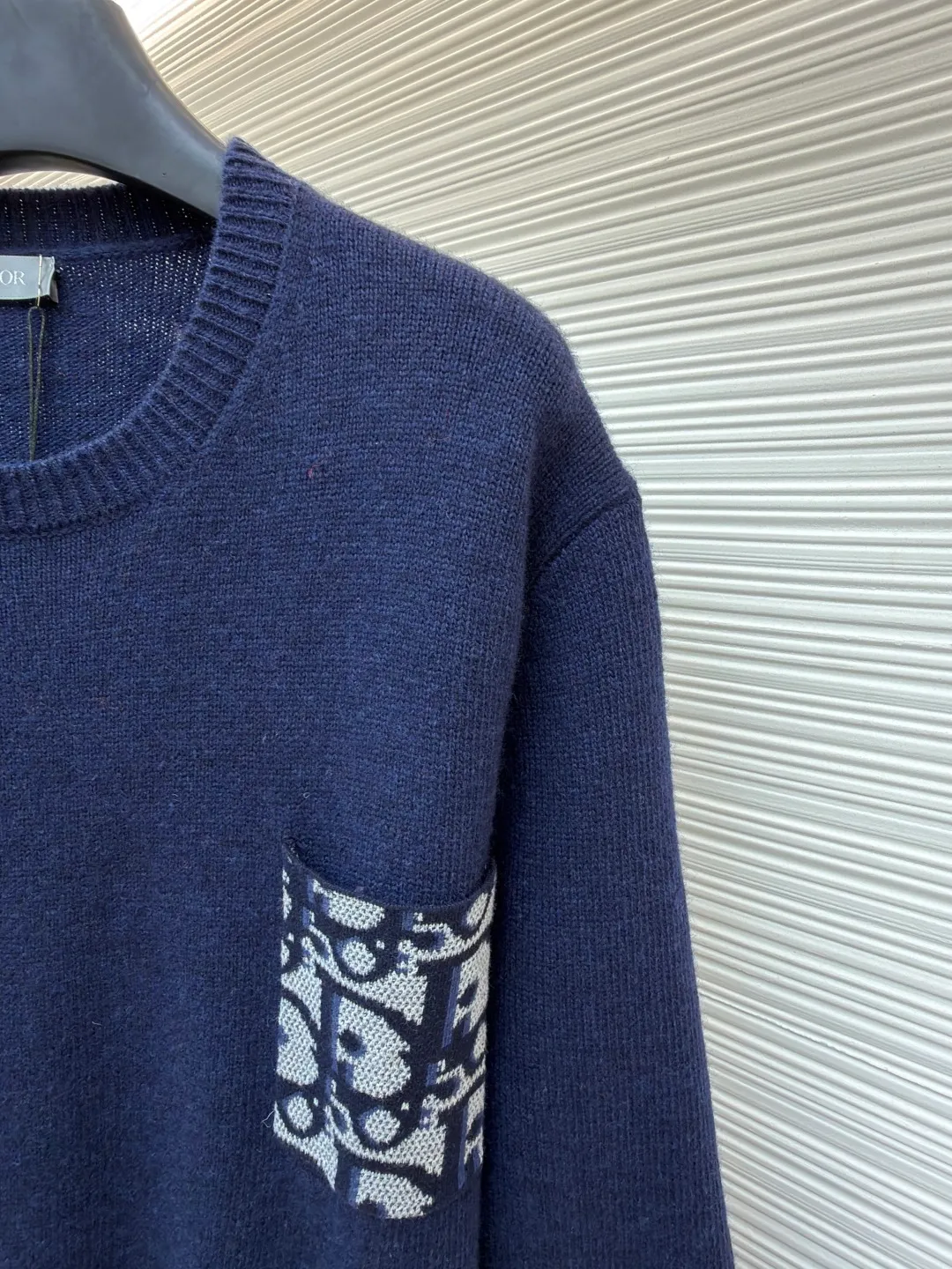 Dior patchwork letter jacquard pocket knitted sweater ●Original version: purchased and developed in 19049 ●Item number: 1682530-B10 ●Fabric: wool fabric ●Technology: jacquard knitting ●Color: navy blue ●Version: fitted version ●Weight: about 560 grams ●Size: S-M-L-XL ●Description: This DIOR The SS26 summer series red sweater is woven with high-quality combed cotton threads and uses plain knitting technology to create the body. The fabric is fine, soft, elastic, breathable and skin-friendly, and is not prone to pilling or snagging. The brand's classic presbyopia pattern pocket on the left side of the body is made using patch printing technology. The printing ink layer is thick and even, and the pattern is clear and three-dimensional. It forms a sharp visual contrast with the red knitted base and highlights the brand recognition. The neckline is a classic round neck design, with double-needle reinforced hemming technology and a custom-made threaded collar, making it durable and not prone to loosening. The cuffs and hem are ribbed in the same color, with moderate elasticity to fit the body shape. The overall cut is a fitted silhouette. The stitching is straight and fine. The customized accessories and three labels are complete. The details and craftsmanship show the level of luxury. It is suitable for daily casual and light business wear scenarios. The overall wiring is straight and delicate, the fabric is comfortable and soft, and the color is consistent without color difference. It can be matched with the same style to create a fashionable look and control various occasions. Customized accessories, complete with three standards, same style for men and women!