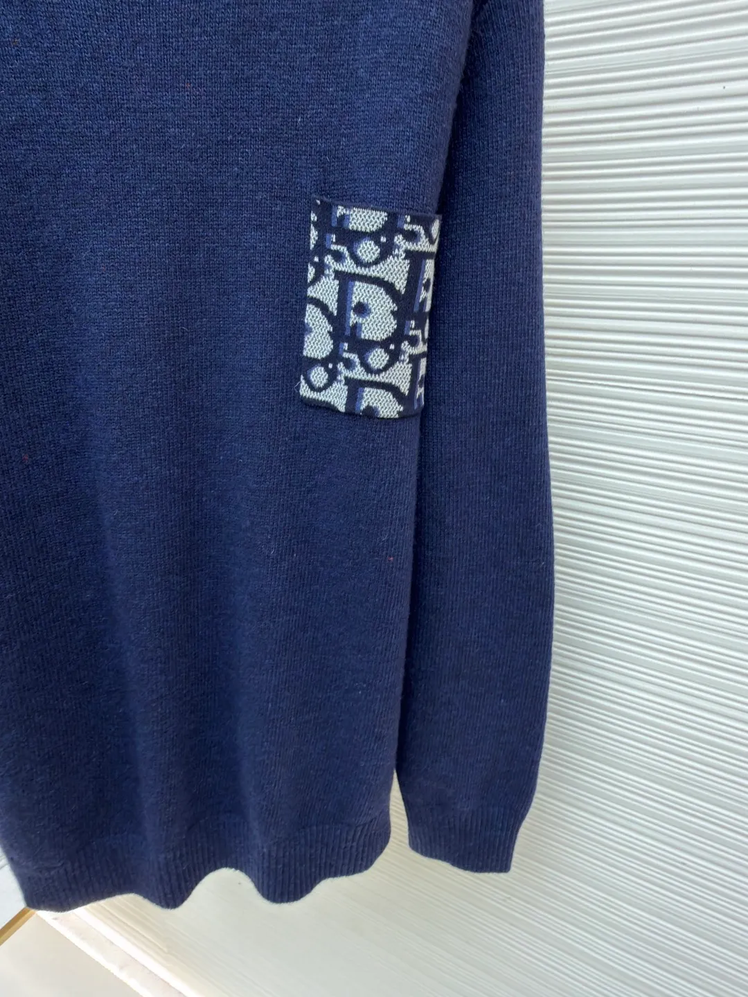 Dior patchwork letter jacquard pocket knitted sweater ●Original version: purchased and developed in 19049 ●Item number: 1682530-B10 ●Fabric: wool fabric ●Technology: jacquard knitting ●Color: navy blue ●Version: fitted version ●Weight: about 560 grams ●Size: S-M-L-XL ●Description: This DIOR The SS26 summer series red sweater is woven with high-quality combed cotton threads and uses plain knitting technology to create the body. The fabric is fine, soft, elastic, breathable and skin-friendly, and is not prone to pilling or snagging. The brand's classic presbyopia pattern pocket on the left side of the body is made using patch printing technology. The printing ink layer is thick and even, and the pattern is clear and three-dimensional. It forms a sharp visual contrast with the red knitted base and highlights the brand recognition. The neckline is a classic round neck design, with double-needle reinforced hemming technology and a custom-made threaded collar, making it durable and not prone to loosening. The cuffs and hem are ribbed in the same color, with moderate elasticity to fit the body shape. The overall cut is a fitted silhouette. The stitching is straight and fine. The customized accessories and three labels are complete. The details and craftsmanship show the level of luxury. It is suitable for daily casual and light business wear scenarios. The overall wiring is straight and delicate, the fabric is comfortable and soft, and the color is consistent without color difference. It can be matched with the same style to create a fashionable look and control various occasions. Customized accessories, complete with three standards, same style for men and women!