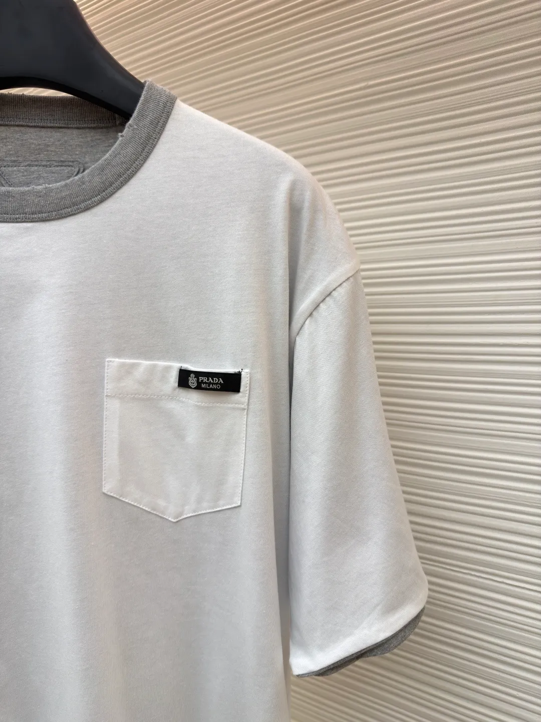 Prada double-sided design logo short sleeves ●Original version: Purchased and developed at 9150 ●Item number: 1682528-A15 ●Material: Velvet-feel plain cotton fabric ●Technology: Precision splicing and seaming production ●Color: Gray ●Version: Fitted version ●Weight: about 280 grams ●Size: S-M-L-XL ●Description: Customized velvet-feel plain cotton, soft and delicate, comfortable and close to the skin, twin aesthetics of gray and white interweaving Wearing the minimalist philosophy of two souls, the cloud white on the front uses Prada label details to define high-end restraint. The contrasting rib collar locks all eyes. The high-grade gray on the back uses the back triangle to highlight the essence of the brand. It is a quiet but unignorable presence. Combined with the frayed design, it is sublimated, filled with artistic atmosphere, double-sided elegance, and leads the trend. Precise splicing and seaming technology uses advanced sewing technology and equipment to ensure that the splicing of each short sleeve is smooth and tight, with smooth lines, and there will be no gaps inside and outside. The neckline is sewn using a computerized double-needle sewing process, using an advanced control system to sew two parallel stitches at the same time. Ensure that the size and shape of the neckline remain consistent, and use positioning and manual fraying. Local friction and wear on the fabric through manual operation will cause a natural damage effect on the surface of the fabric. The overall wiring is straight and delicate, the fabric is comfortable and soft, and the color is consistent without color difference. It can be matched with the same style to create a fashionable look and control various occasions. Customized accessories, complete with three standards, same style for men and women!