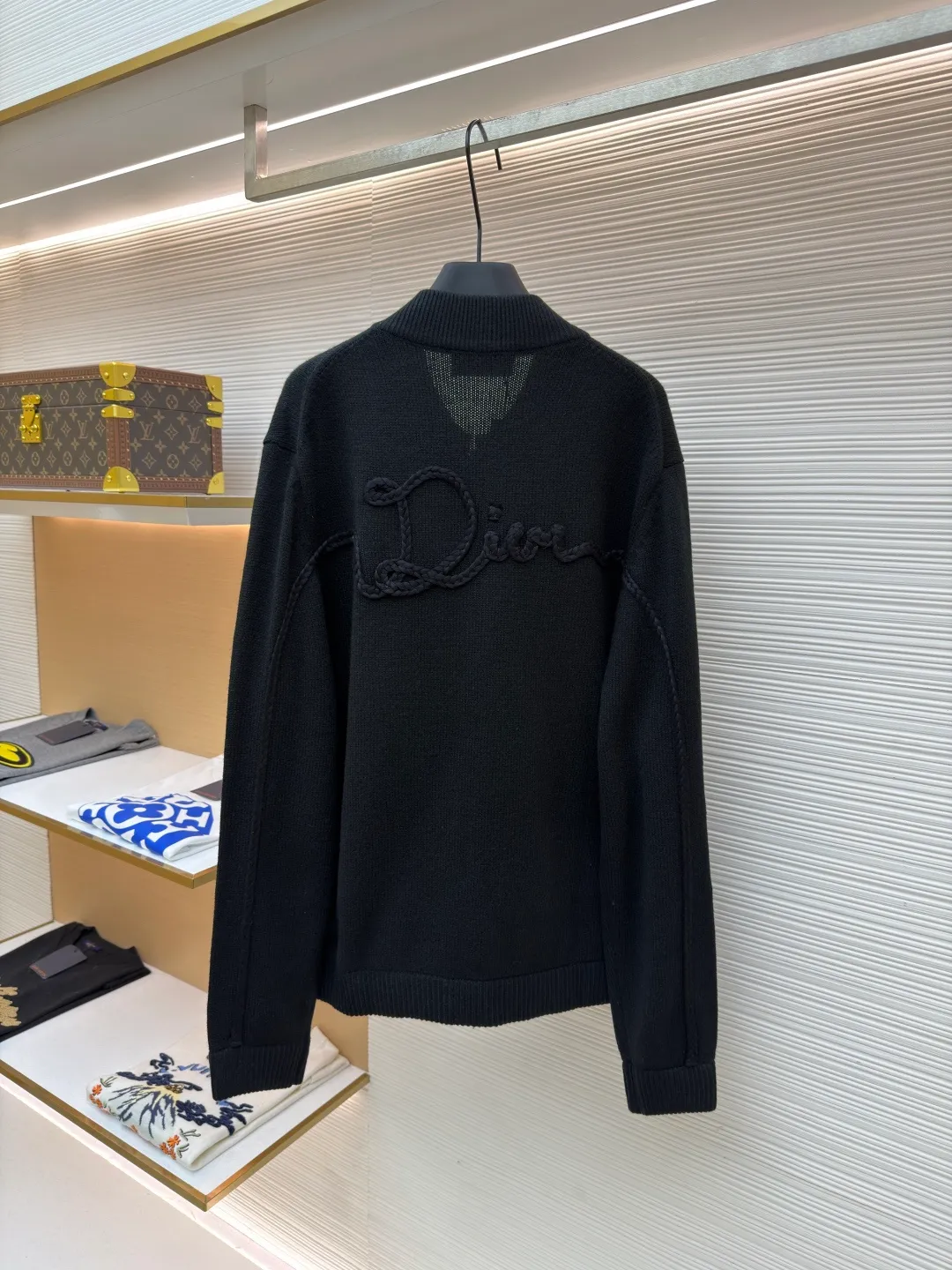 Dior letter embroidered wool knitted cardigan ●Original version: Purchased and developed by 18684 ●Item number: 1682138-C05 ●Fabric: wool blended fabric ●Technology: knitting ●Color: black ●Version: fitted version ●Weight: about 755 grams ●Size: S-M-L-XL ●Description: This Dior black knitted zipper cardigan is made of high-count worsted wool and mulberry silk blended yarn. It is woven with plain knitting technology on an Italian 16-needle computerized flat machine. The yarn is first treated with anti-pilling and pre-shrunk to make the garment soft and resistant to deformation. The Dior logo on the front chest adopts dark embroidery technology, using matte embroidery thread of the same color, completed with 0.1mm fine stitching, which is low-key and rich in texture; the three-dimensional Dior letters on the back use hand-made rope embroidery techniques, and the woven rope straps are fixed segment by section according to the outline of the version, forming a 3D relief effect. The connection between the rope strap and the body adopts invisible locking technology, without any abrupt threads. The inner side of the collar is spliced ​​with breathable mesh fabric, the metal zipper is made of custom matte nickel material, and the teeth are treated with wear-resistant treatment. The ribbed edges of the cuffs and hem have built-in elastic spandex yarn, and are hand-ironed and shaped. Every craftsmanship detail is in line with Dior's high-end ready-to-wear production standards. The overall wiring is straight and delicate, the fabric is comfortable and soft, and the color is consistent without color difference. It can be matched with the same style to create a fashionable look and control various occasions. Customized accessories, complete with three standards, same style for men and women!