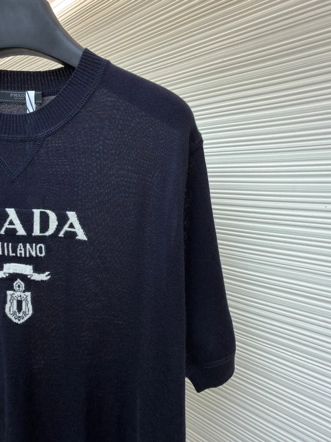Prada classic LOGO jacquard wool round neck short sleeves ●Original version: purchased and developed by 11988 ●Item number: 1682516-A45 ●Fabric: wool fabric ●Technology: jacquard production ●Color: black ●Version: fitted version ●Weight: about 150 grams ●Size: 46-48-50-52 ●Description: This PRADA gray knitted short-sleeve is woven with high-quality combed cotton threads. The body is made of vertical pit knitting technology. The texture is three-dimensional and elastic. It is soft and breathable when worn next to the skin. It has good drape and stiffness, and is not prone to pilling and deformation. The brand letters and badge pattern on the front of the garment are made with precision embroidery technology. The embroidery thread is made of imported high-gloss yarn. The stitches are dense and even, and the pattern is three-dimensional and clear. It forms a texture contrast with the knitted base to highlight the brand recognition. The neckline is a classic round neck design, with double-needle reinforced hemming technology and a customized threaded collar, which is durable and not easy to loosen. The cuffs and hem are ribbed in the same color. The overall cut is a loose silhouette. The stitching is straight and fine. The customized accessories and three standards are complete. The detailed craftsmanship shows the level of luxury. It is suitable for casual daily and light business wear scenarios. The overall wiring is straight and delicate, the fabric is comfortable and soft, and the color is consistent without color difference. It can be matched with the same style to create a fashionable look and control various occasions. Customized accessories, complete with three standards, same style for men and women!