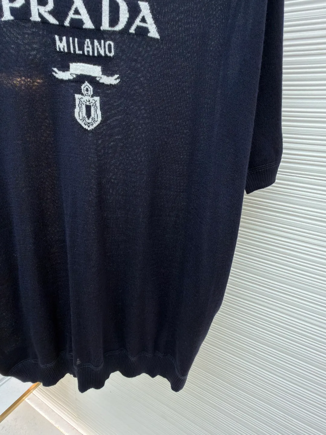 Prada classic LOGO jacquard wool round neck short sleeves ●Original version: purchased and developed by 11988 ●Item number: 1682516-A45 ●Fabric: wool fabric ●Technology: jacquard production ●Color: black ●Version: fitted version ●Weight: about 150 grams ●Size: 46-48-50-52 ●Description: This PRADA gray knitted short-sleeve is woven with high-quality combed cotton threads. The body is made of vertical pit knitting technology. The texture is three-dimensional and elastic. It is soft and breathable when worn next to the skin. It has good drape and stiffness, and is not prone to pilling and deformation. The brand letters and badge pattern on the front of the garment are made with precision embroidery technology. The embroidery thread is made of imported high-gloss yarn. The stitches are dense and even, and the pattern is three-dimensional and clear. It forms a texture contrast with the knitted base to highlight the brand recognition. The neckline is a classic round neck design, with double-needle reinforced hemming technology and a customized threaded collar, which is durable and not easy to loosen. The cuffs and hem are ribbed in the same color. The overall cut is a loose silhouette. The stitching is straight and fine. The customized accessories and three standards are complete. The detailed craftsmanship shows the level of luxury. It is suitable for casual daily and light business wear scenarios. The overall wiring is straight and delicate, the fabric is comfortable and soft, and the color is consistent without color difference. It can be matched with the same style to create a fashionable look and control various occasions. Customized accessories, complete with three standards, same style for men and women!