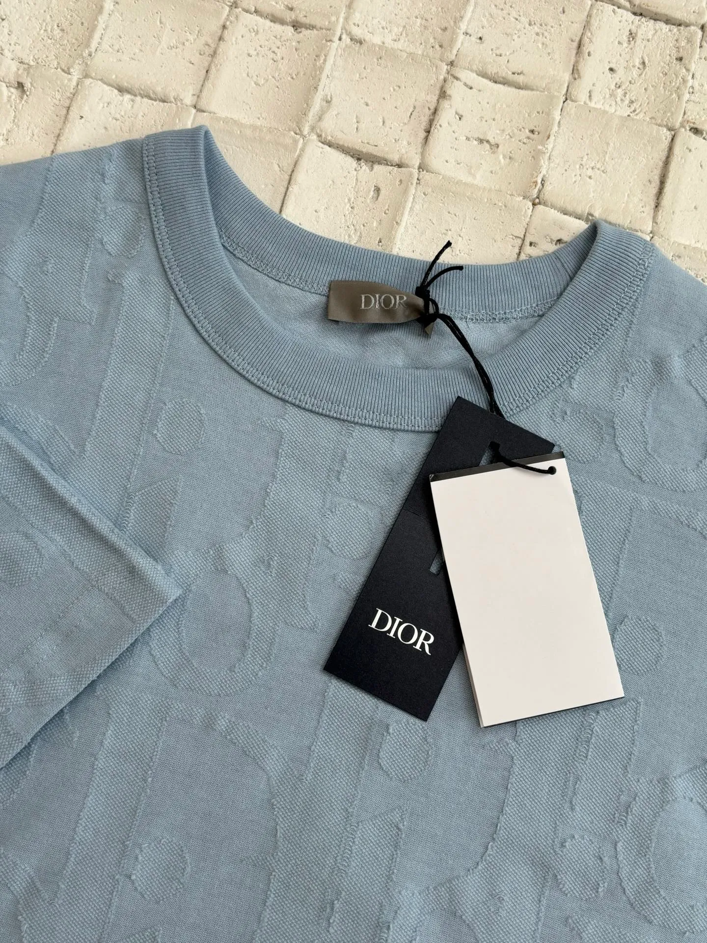 🅿️296 Dio*/Dior 25Ss new line-cut jacquard round-neck short-sleeved T-shirt. Pure cotton plain weave fabric, woven with 32S double-ply pure cotton yarn. The fabric has high abrasion resistance while retaining the moisture absorption and breathability of pure cotton. The plain weave has a tight structure and a smooth surface, but it feels relatively stiff and supports the stiffness of the version. Jacquard pattern, line-cut jacquard technology, full-width Oblique jacquard pattern The relief effect is formed through the deep integration of full-width jacquard and shearing process. The jacquard structure provides a three-dimensional skeleton, and the shearing process strengthens the local texture. Electronic jacquard machine weaves complex patterns on the entire fabric, forming a three-dimensional concave and convex texture to achieve the integration of texture and pattern. The raised jacquard is directionally sheared to form a relief effect, enhancing the tactile level and visual contrast. Size: S/M/L/XL