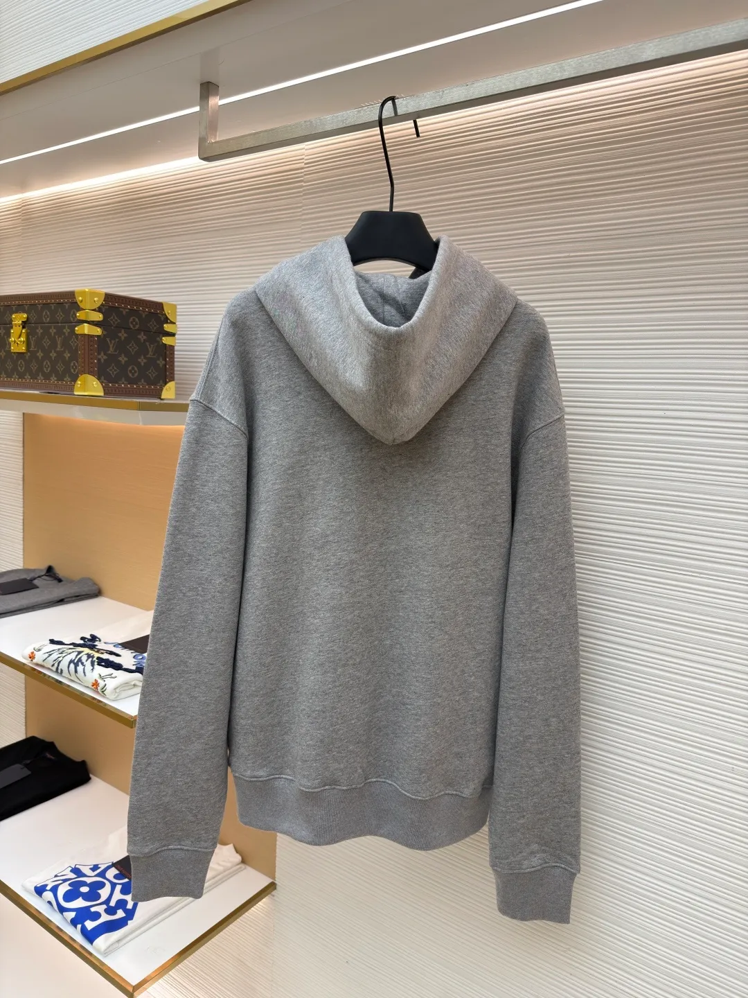 Dior classic logo embroidered hooded sweatshirt ●Item number: 1682332-A75 ●Material: cotton fabric ●Technology: embroidery production ●Color: gray ●Version: fitted version ●Weight: about 645 grams ●Size: XS-S-M-L ●Description: It adopts a fleece fabric structure of 26 counts of double yarn + 10S plush bottom, with a weight of 380g/㎡, and 21 counts of 1x1 ribs with a weight of 470g/㎡. It is used for the cuffs and hem. Its extremely high weight ensures the ultimate thickness, stiffness and deformation resistance of these closing parts, forming a unified and strong outline with the body. The fabric is a heavyweight and high-quality sweatshirt fabric. The 26-count double yarn forms a smooth, delicate and strong outer surface of the fabric, ensuring good color fastness and appearance. The 10S plush base undergoes a precise fleece or brushing process to form a layer of rich, dense and uniform fluff on the inside of the fabric. This makes the sweatshirt have a crisp and skeletal feel on the outside and an extremely soft and warm feel on the inside. White tone twill needle embroidery process. Needle embroidery is a straight line embroidery with stitches closely connected and evenly arranged. It is often used to outline clear and sharp outlines. This stitch is used to embroider a diagonal stripe pattern with a certain angle and width. Use white embroidery thread to follow the preset diagonal trajectory and perform precise embroidery with high-density stitches. On the high-weight fabric base, simple, exquisite and three-dimensional line decoration is created. The contrast between white and fabric color is sharp, and the slightly convex texture brought by the embroidery adds a visual and tactile layer, effectively enhancing the exquisite style of the basic sweatshirt. The overall wiring is straight and delicate, the fabric is comfortable and soft, and the color is consistent without color difference. It can be matched with the same style to create a fashionable look and control various occasions. Customized accessories, complete with three standards, same style for men and women!