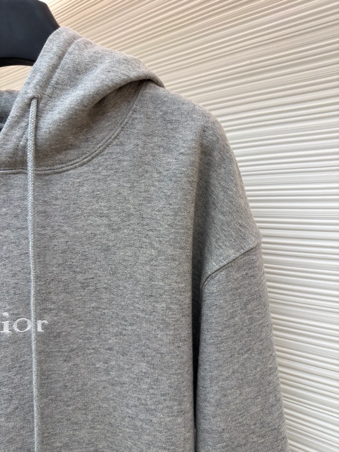 Dior classic logo embroidered hooded sweatshirt ●Item number: 1682332-A75 ●Material: cotton fabric ●Technology: embroidery production ●Color: gray ●Version: fitted version ●Weight: about 645 grams ●Size: XS-S-M-L ●Description: It adopts a fleece fabric structure of 26 counts of double yarn + 10S plush bottom, with a weight of 380g/㎡, and 21 counts of 1x1 ribs with a weight of 470g/㎡. It is used for the cuffs and hem. Its extremely high weight ensures the ultimate thickness, stiffness and deformation resistance of these closing parts, forming a unified and strong outline with the body. The fabric is a heavyweight and high-quality sweatshirt fabric. The 26-count double yarn forms a smooth, delicate and strong outer surface of the fabric, ensuring good color fastness and appearance. The 10S plush base undergoes a precise fleece or brushing process to form a layer of rich, dense and uniform fluff on the inside of the fabric. This makes the sweatshirt have a crisp and skeletal feel on the outside and an extremely soft and warm feel on the inside. White tone twill needle embroidery process. Needle embroidery is a straight line embroidery with stitches closely connected and evenly arranged. It is often used to outline clear and sharp outlines. This stitch is used to embroider a diagonal stripe pattern with a certain angle and width. Use white embroidery thread to follow the preset diagonal trajectory and perform precise embroidery with high-density stitches. On the high-weight fabric base, simple, exquisite and three-dimensional line decoration is created. The contrast between white and fabric color is sharp, and the slightly convex texture brought by the embroidery adds a visual and tactile layer, effectively enhancing the exquisite style of the basic sweatshirt. The overall wiring is straight and delicate, the fabric is comfortable and soft, and the color is consistent without color difference. It can be matched with the same style to create a fashionable look and control various occasions. Customized accessories, complete with three standards, same style for men and women!