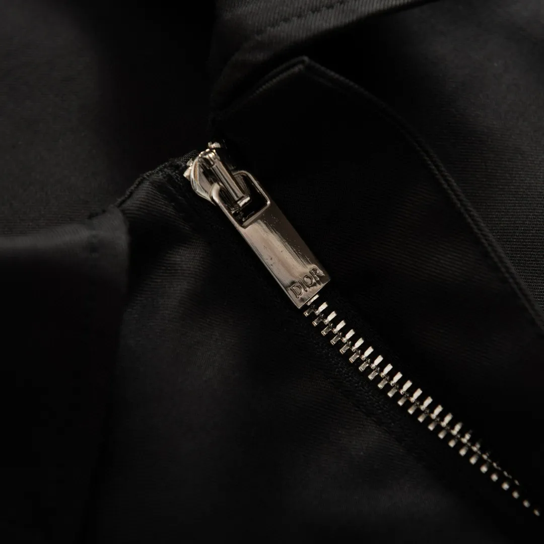 🅿️590 [Exclusive supply] CD icon pocket embroidered lapel jacket. The fabric is made of black gabardine fabric, with a smooth and delicate surface, soft touch, and an elegant sheen. Its tight textile construction makes it resistant to wrinkles, abrasion and drape. The wool component makes it warm and breathable. Gabardine fabric is not easy to pill, has good stain resistance, and is easy to care for daily. The modern fit has a slim fit and a hidden zip closure adds understated sophistication. High-precision sewing technology ensures a perfect fit between the zipper and the fabric. The lapel design of traditional shirts still meets the needs of formal occasions. There is a patch pocket on the chest and is decorated with CD icon embroidery, which highlights the brand's iconic elements. The bag opening also has a hidden zipper opening, and the bag opening is reinforced with pocket knotting technology at the beginning and end. Tight stitching at the edge of the bag body makes it strong and beautiful. There are side pockets on the left and right sides, and the pocket openings are only 0.5 cm hemmed, which retains the smoothness of the overall lines without losing practicality. The double-button design of traditional shirt cuffs makes the cuffs fit more closely on the wrist and prevent them from loosening. Size:46/48/50/52