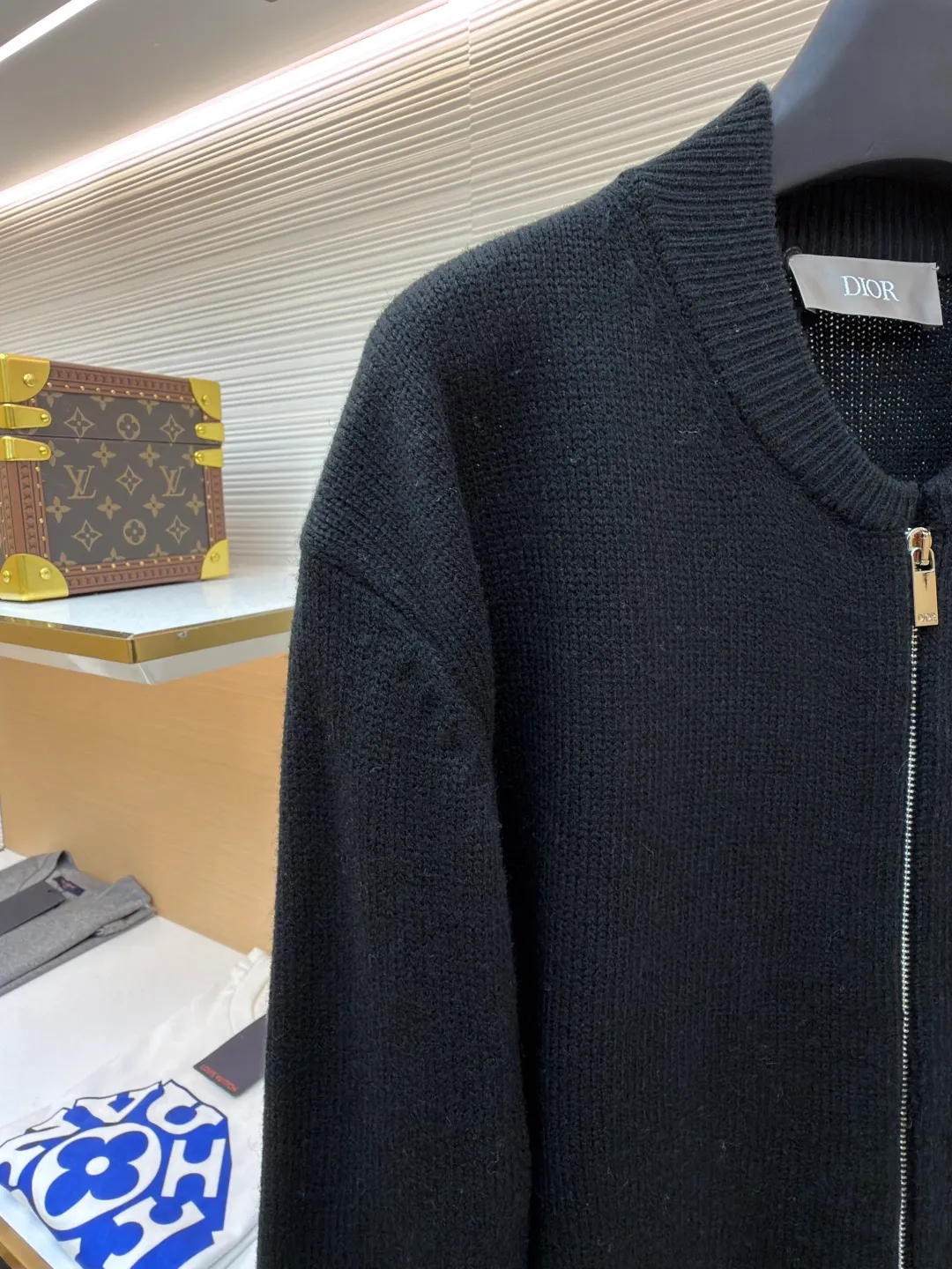 Dior letter embroidered wool knitted cardigan ●Original version: Purchased and developed by 18684 ●Item number: 1682138-C05 ●Fabric: wool blended fabric ●Technology: knitting ●Color: black ●Version: fitted version ●Weight: about 755 grams ●Size: S-M-L-XL ●Description: This Dior black knitted zipper cardigan is made of high-count worsted wool and mulberry silk blended yarn. It is woven with plain knitting technology on an Italian 16-needle computerized flat machine. The yarn is first treated with anti-pilling and pre-shrunk to make the garment soft and resistant to deformation. The Dior logo on the front chest adopts dark embroidery technology, using matte embroidery thread of the same color, completed with 0.1mm fine stitching, which is low-key and rich in texture; the three-dimensional Dior letters on the back use hand-made rope embroidery techniques, and the woven rope straps are fixed segment by section according to the outline of the version, forming a 3D relief effect. The connection between the rope strap and the body adopts invisible locking technology, without any abrupt threads. The inner side of the collar is spliced ​​with breathable mesh fabric, the metal zipper is made of custom matte nickel material, and the teeth are treated with wear-resistant treatment. The ribbed edges of the cuffs and hem have built-in elastic spandex yarn, and are hand-ironed and shaped. Every craftsmanship detail is in line with Dior's high-end ready-to-wear production standards. The overall wiring is straight and delicate, the fabric is comfortable and soft, and the color is consistent without color difference. It can be matched with the same style to create a fashionable look and control various occasions. Customized accessories, complete with three standards, same style for men and women!