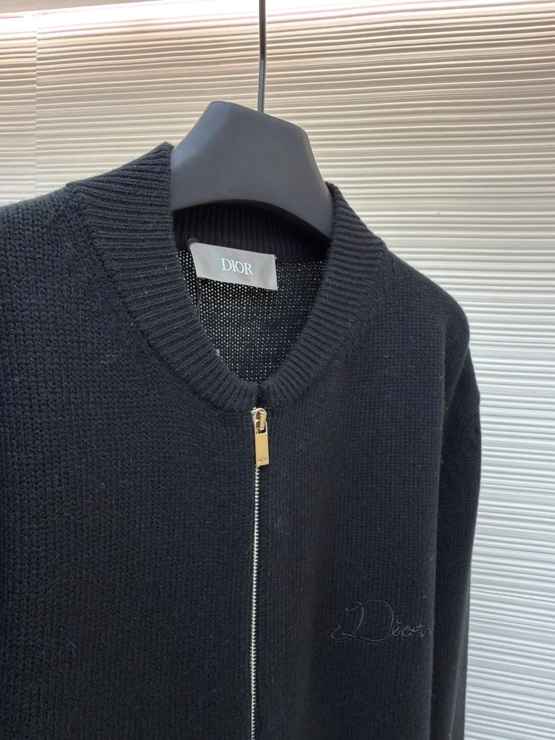 Dior letter embroidered wool knitted cardigan ●Original version: Purchased and developed by 18684 ●Item number: 1682138-C05 ●Fabric: wool blended fabric ●Technology: knitting ●Color: black ●Version: fitted version ●Weight: about 755 grams ●Size: S-M-L-XL ●Description: This Dior black knitted zipper cardigan is made of high-count worsted wool and mulberry silk blended yarn. It is woven with plain knitting technology on an Italian 16-needle computerized flat machine. The yarn is first treated with anti-pilling and pre-shrunk to make the garment soft and resistant to deformation. The Dior logo on the front chest adopts dark embroidery technology, using matte embroidery thread of the same color, completed with 0.1mm fine stitching, which is low-key and rich in texture; the three-dimensional Dior letters on the back use hand-made rope embroidery techniques, and the woven rope straps are fixed segment by section according to the outline of the version, forming a 3D relief effect. The connection between the rope strap and the body adopts invisible locking technology, without any abrupt threads. The inner side of the collar is spliced ​​with breathable mesh fabric, the metal zipper is made of custom matte nickel material, and the teeth are treated with wear-resistant treatment. The ribbed edges of the cuffs and hem have built-in elastic spandex yarn, and are hand-ironed and shaped. Every craftsmanship detail is in line with Dior's high-end ready-to-wear production standards. The overall wiring is straight and delicate, the fabric is comfortable and soft, and the color is consistent without color difference. It can be matched with the same style to create a fashionable look and control various occasions. Customized accessories, complete with three standards, same style for men and women!