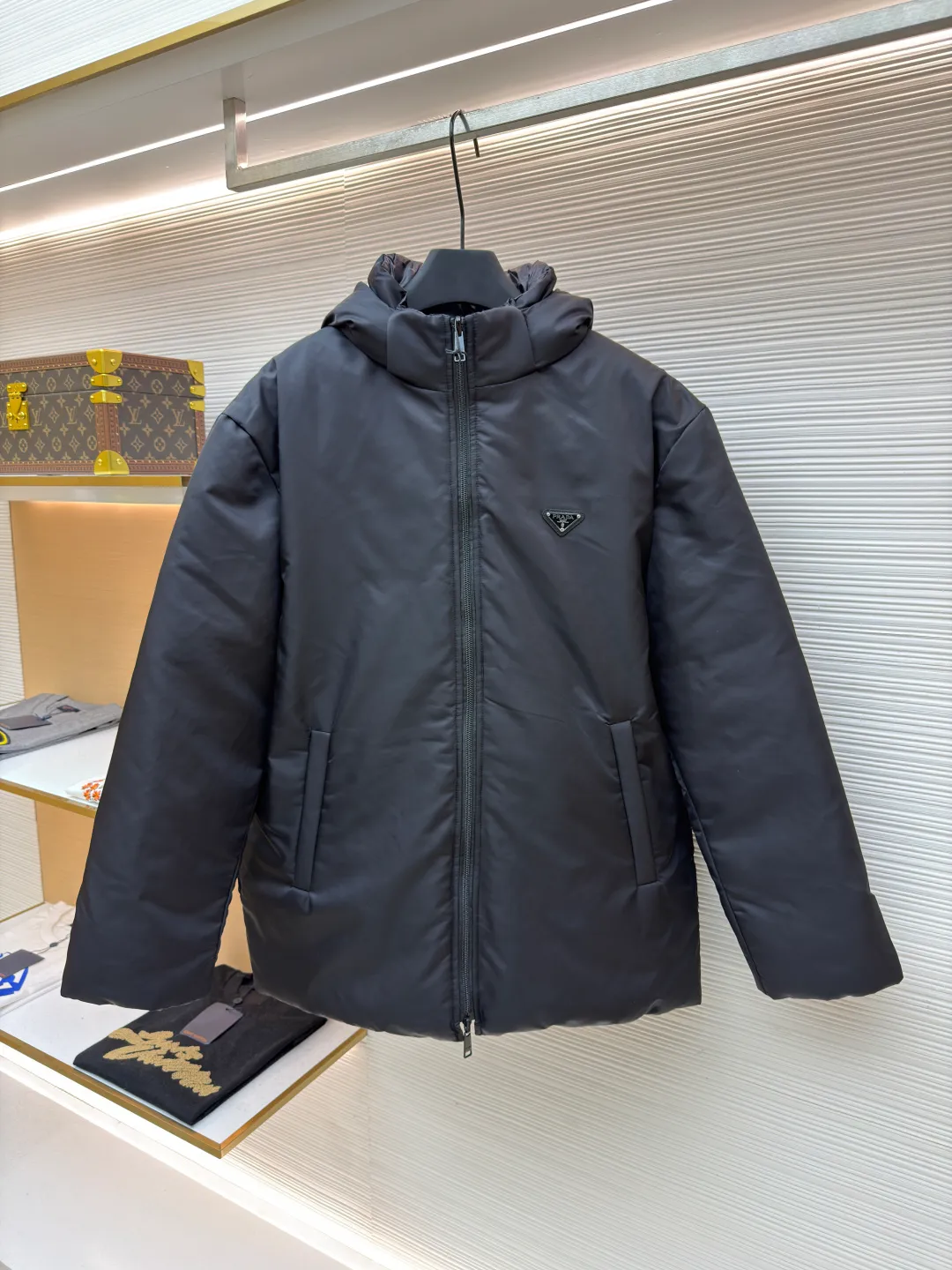 Prada mid-length nylon hooded down jacket ●Original version: purchased and developed for 15999 ●Item number: 1681587-D35 ●Fabric: white duck down fabric ●Technology: mechanical down filling ●Color: black ●Version: fitted version ●Weight: about 1155 grams ●Size: S-M-L-XL ●Description: Re-Nylon short down jacket uses environmentally friendly Re-Nylon material, the fabric density is very high It has strong tear resistance, strong stiffness and wear resistance. It is different from the Bird brand's hard shell, it is softer and has a very strong sense of functionality. Double-sided design: The biggest highlight of this down jacket is its double-sided design, which allows one piece of clothing to show two different styles and shapes, greatly increasing the diversity and fashion sense of wearing. Detachable hood: The down jacket is equipped with a detachable nylon hood, which users can easily remove or install according to weather changes or personal preferences, which is both practical and convenient. The details are exquisitely processed: the zipper design is simple and elegant, easy to operate; the closing design of the cuffs and hem effectively prevents the intrusion of cold wind, improving the warmth and comfort of wearing. All the hangtags, wash marks, air holes, snap buttons, and chest labels are all custom-made using original one-to-one molds.  The overall wiring is straight and delicate, the fabric is comfortable and soft, and the color is consistent without color difference. It can be matched with the same style to create a fashionable look and control various occasions. Customized accessories, complete with three standards, same style for men and women!
