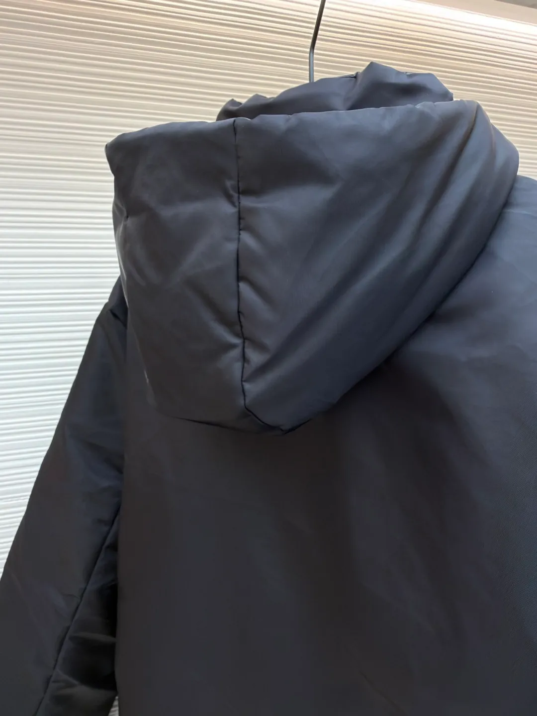 Prada mid-length nylon hooded down jacket ●Original version: purchased and developed for 15999 ●Item number: 1681587-D35 ●Fabric: white duck down fabric ●Technology: mechanical down filling ●Color: black ●Version: fitted version ●Weight: about 1155 grams ●Size: S-M-L-XL ●Description: Re-Nylon short down jacket uses environmentally friendly Re-Nylon material, the fabric density is very high It has strong tear resistance, strong stiffness and wear resistance. It is different from the Bird brand's hard shell, it is softer and has a very strong sense of functionality. Double-sided design: The biggest highlight of this down jacket is its double-sided design, which allows one piece of clothing to show two different styles and shapes, greatly increasing the diversity and fashion sense of wearing. Detachable hood: The down jacket is equipped with a detachable nylon hood, which users can easily remove or install according to weather changes or personal preferences, which is both practical and convenient. The details are exquisitely processed: the zipper design is simple and elegant, easy to operate; the closing design of the cuffs and hem effectively prevents the intrusion of cold wind, improving the warmth and comfort of wearing. All the hangtags, wash marks, air holes, snap buttons, and chest labels are all custom-made using original one-to-one molds.  The overall wiring is straight and delicate, the fabric is comfortable and soft, and the color is consistent without color difference. It can be matched with the same style to create a fashionable look and control various occasions. Customized accessories, complete with three standards, same style for men and women!