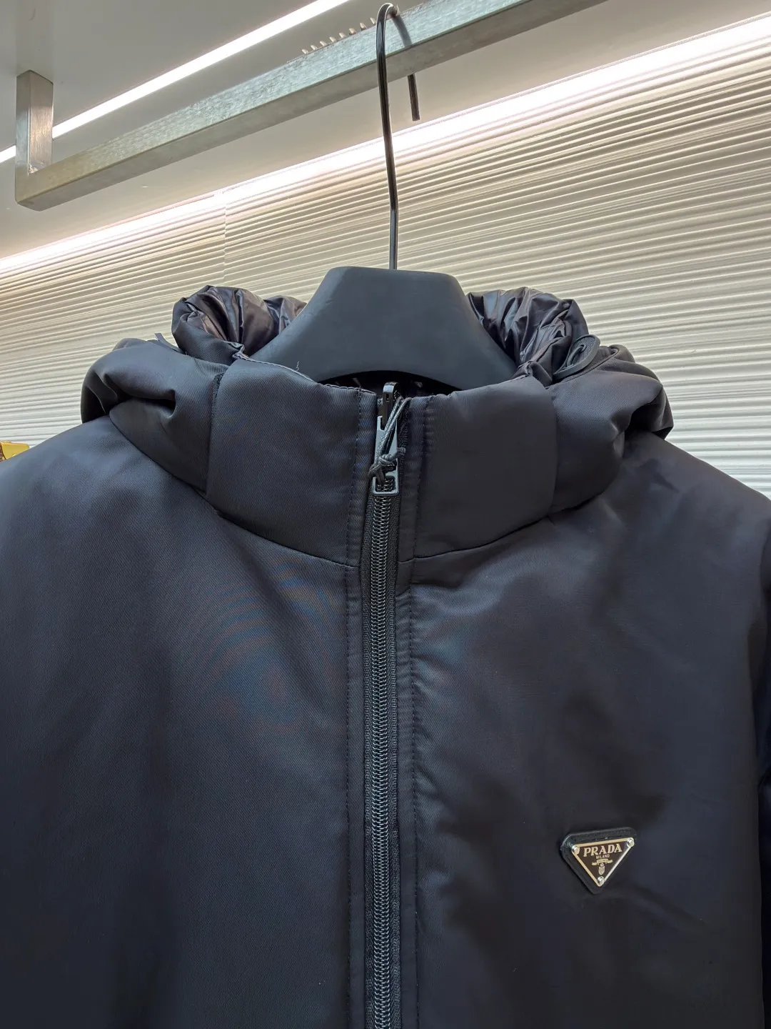 Prada mid-length nylon hooded down jacket ●Original version: purchased and developed for 15999 ●Item number: 1681587-D35 ●Fabric: white duck down fabric ●Technology: mechanical down filling ●Color: black ●Version: fitted version ●Weight: about 1155 grams ●Size: S-M-L-XL ●Description: Re-Nylon short down jacket uses environmentally friendly Re-Nylon material, the fabric density is very high It has strong tear resistance, strong stiffness and wear resistance. It is different from the Bird brand's hard shell, it is softer and has a very strong sense of functionality. Double-sided design: The biggest highlight of this down jacket is its double-sided design, which allows one piece of clothing to show two different styles and shapes, greatly increasing the diversity and fashion sense of wearing. Detachable hood: The down jacket is equipped with a detachable nylon hood, which users can easily remove or install according to weather changes or personal preferences, which is both practical and convenient. The details are exquisitely processed: the zipper design is simple and elegant, easy to operate; the closing design of the cuffs and hem effectively prevents the intrusion of cold wind, improving the warmth and comfort of wearing. All the hangtags, wash marks, air holes, snap buttons, and chest labels are all custom-made using original one-to-one molds.  The overall wiring is straight and delicate, the fabric is comfortable and soft, and the color is consistent without color difference. It can be matched with the same style to create a fashionable look and control various occasions. Customized accessories, complete with three standards, same style for men and women!