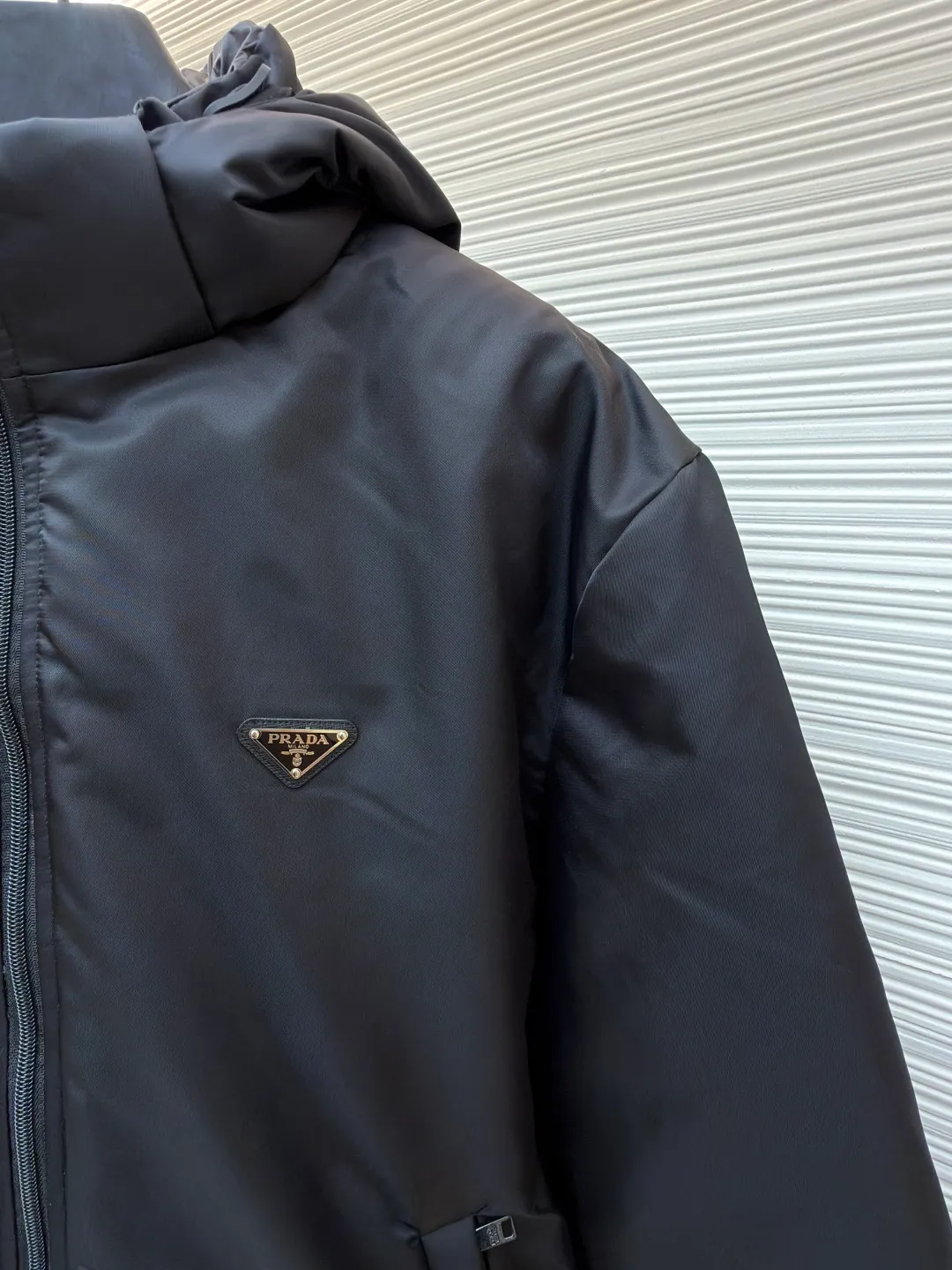Prada mid-length nylon hooded down jacket ●Original version: purchased and developed for 15999 ●Item number: 1681587-D35 ●Fabric: white duck down fabric ●Technology: mechanical down filling ●Color: black ●Version: fitted version ●Weight: about 1155 grams ●Size: S-M-L-XL ●Description: Re-Nylon short down jacket uses environmentally friendly Re-Nylon material, the fabric density is very high It has strong tear resistance, strong stiffness and wear resistance. It is different from the Bird brand's hard shell, it is softer and has a very strong sense of functionality. Double-sided design: The biggest highlight of this down jacket is its double-sided design, which allows one piece of clothing to show two different styles and shapes, greatly increasing the diversity and fashion sense of wearing. Detachable hood: The down jacket is equipped with a detachable nylon hood, which users can easily remove or install according to weather changes or personal preferences, which is both practical and convenient. The details are exquisitely processed: the zipper design is simple and elegant, easy to operate; the closing design of the cuffs and hem effectively prevents the intrusion of cold wind, improving the warmth and comfort of wearing. All the hangtags, wash marks, air holes, snap buttons, and chest labels are all custom-made using original one-to-one molds.  The overall wiring is straight and delicate, the fabric is comfortable and soft, and the color is consistent without color difference. It can be matched with the same style to create a fashionable look and control various occasions. Customized accessories, complete with three standards, same style for men and women!