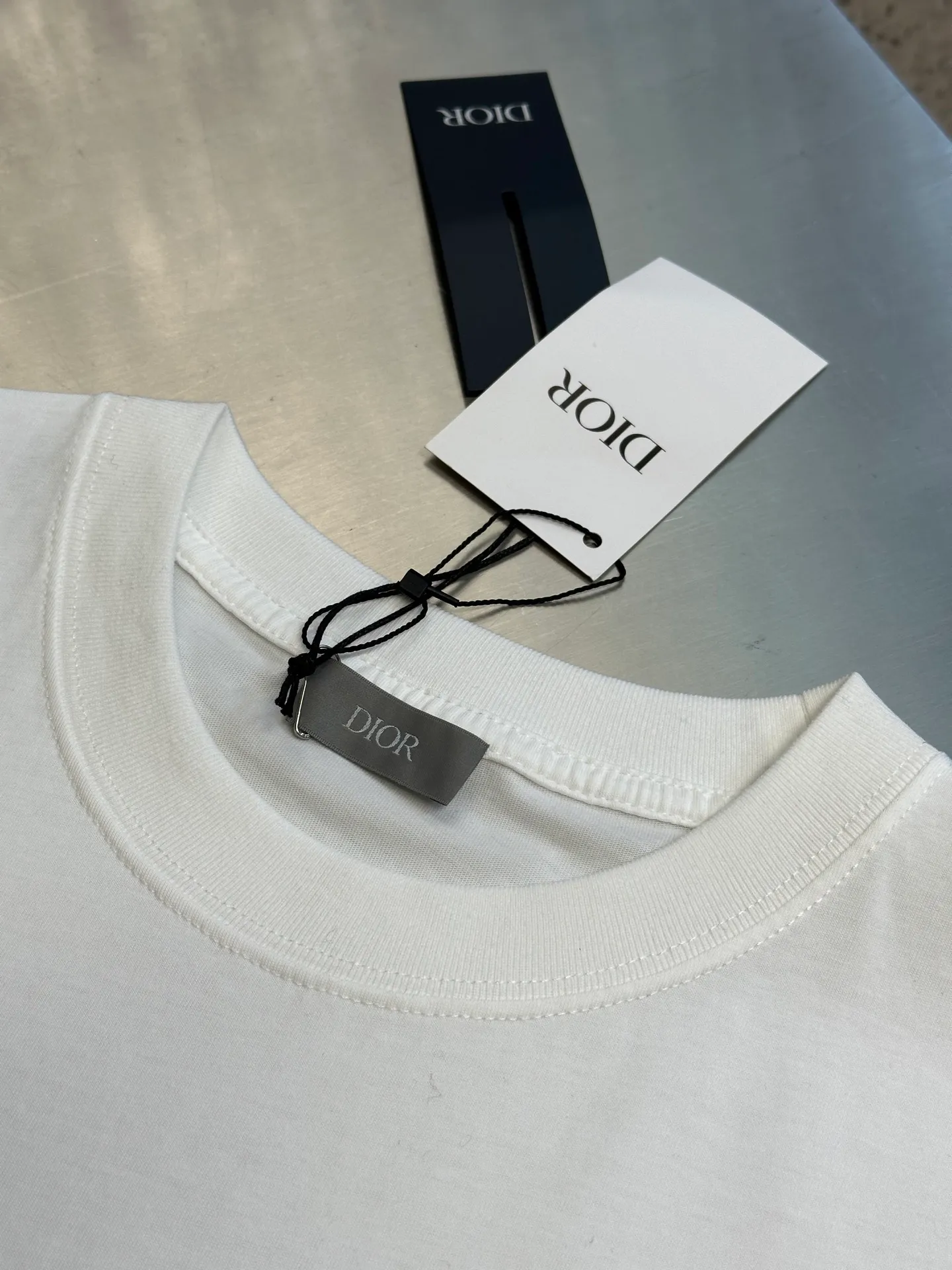 🅿️260 Dior Love Series Pocket Embroidery Round Neck Short Sleeve Cotton Jersey Fabric. Made of 24S special woven compact cotton fabric, 185g; with 32S double yarn thread, 300g. The strength of compact yarn is higher than that of traditional single yarn. The single fibers in compact yarn are closely arranged, which helps to improve the strength of the yarn. The ends of the fibers are all twisted into the yarn, so the yarn is very tight and the yarn has a smooth appearance with less hairiness. Compact spinning yarn has higher strength and less hairiness, making it less prone to fraying.  The chest is decorated with embroidery patterns, and the main body adopts precision stitch embroidery technology; the embroidery is very fine and dense, with clear patterns and strong lines and three-dimensionality. The linen material embroidery thread is combined with encrypted processing, and the embroidery body has a subtle matte visual texture; the embroidery effect is three-dimensional and full. The flat embroidery has a unique needle-to-needle design, and the embroidery is very fine and dense. The overall stitching is fine, with consistent fineness and texture, adding a sense of layering to the simple design.  Standard crew neck, short sleeve fit. The neckline is rounded and arc-shaped, suitable for various face shapes and body shapes; the sleeve length is moderate and ends just above the elbow, showing a smart and neat image. The slim fit can show off the wearer's body curves without sacrificing comfort. The collar, cuffs, hem and other parts are all sewn with fine double-needle stitching.  size：xs s m l