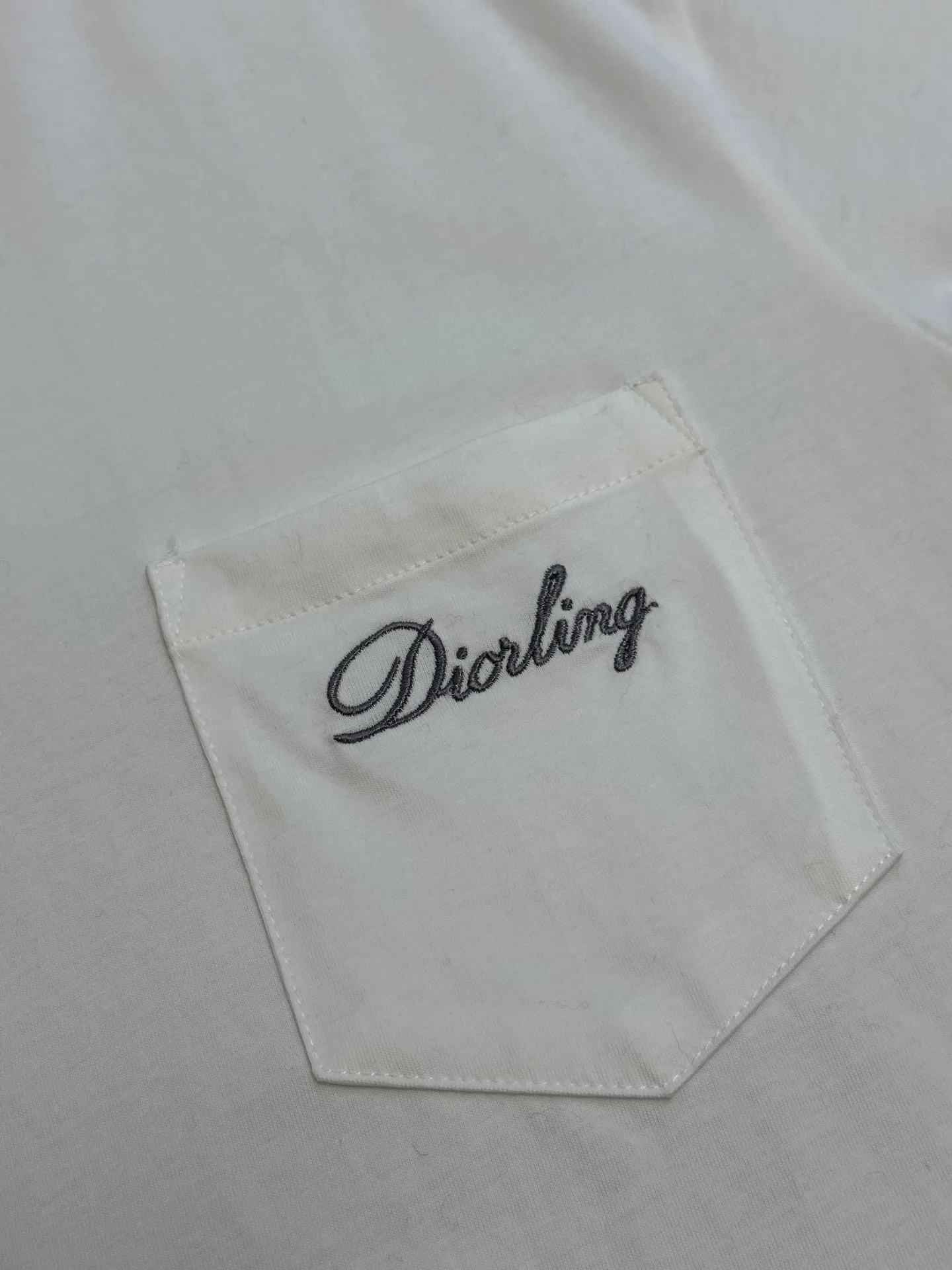 🅿️260 Dior Love Series Pocket Embroidery Round Neck Short Sleeve Cotton Jersey Fabric. Made of 24S special woven compact cotton fabric, 185g; with 32S double yarn thread, 300g. The strength of compact yarn is higher than that of traditional single yarn. The single fibers in compact yarn are closely arranged, which helps to improve the strength of the yarn. The ends of the fibers are all twisted into the yarn, so the yarn is very tight and the yarn has a smooth appearance with less hairiness. Compact spinning yarn has higher strength and less hairiness, making it less prone to fraying.  The chest is decorated with embroidery patterns, and the main body adopts precision stitch embroidery technology; the embroidery is very fine and dense, with clear patterns and strong lines and three-dimensionality. The linen material embroidery thread is combined with encrypted processing, and the embroidery body has a subtle matte visual texture; the embroidery effect is three-dimensional and full. The flat embroidery has a unique needle-to-needle design, and the embroidery is very fine and dense. The overall stitching is fine, with consistent fineness and texture, adding a sense of layering to the simple design.  Standard crew neck, short sleeve fit. The neckline is rounded and arc-shaped, suitable for various face shapes and body shapes; the sleeve length is moderate and ends just above the elbow, showing a smart and neat image. The slim fit can show off the wearer's body curves without sacrificing comfort. The collar, cuffs, hem and other parts are all sewn with fine double-needle stitching.  size：xs s m l