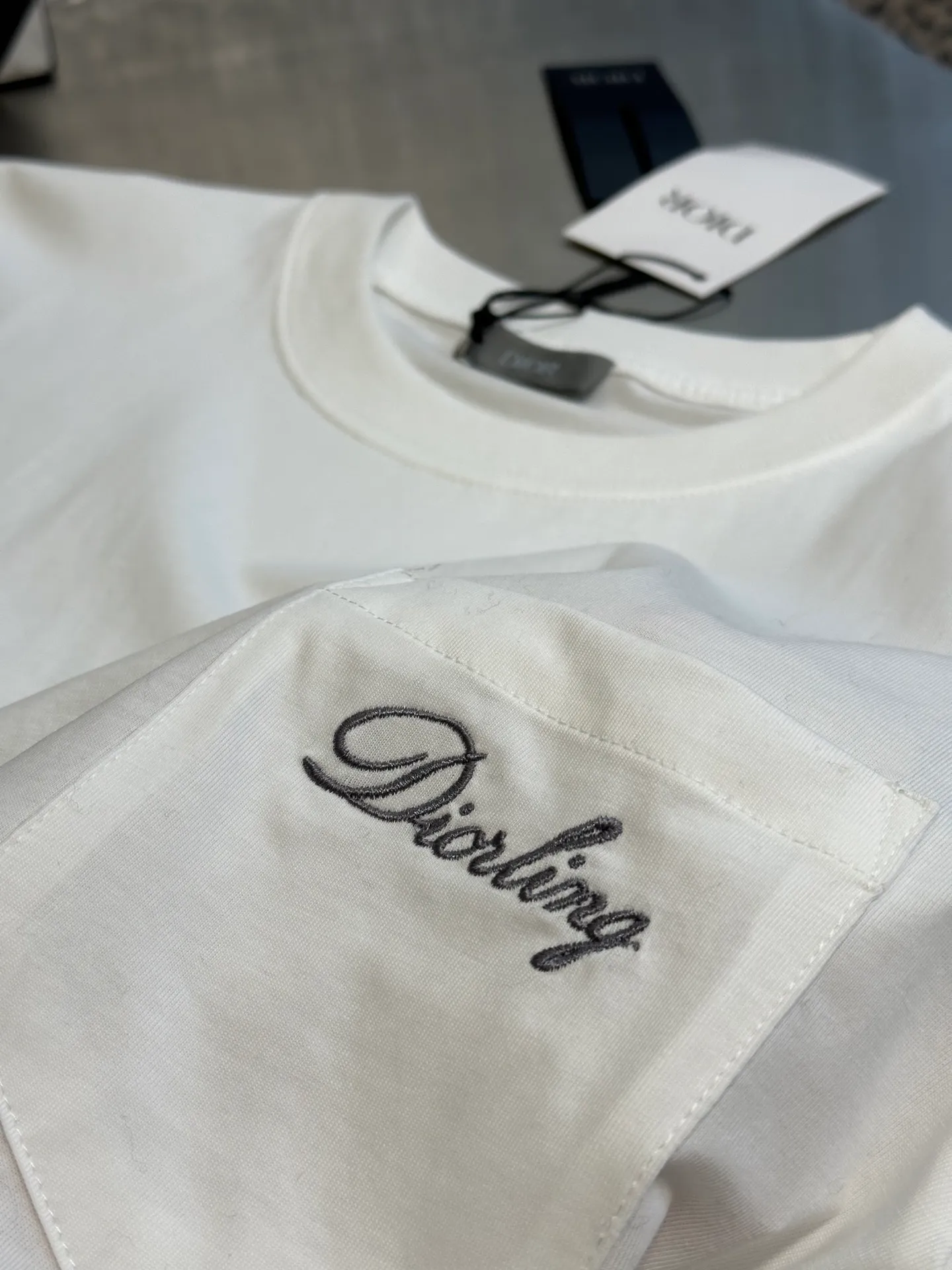 🅿️260 Dior Love Series Pocket Embroidery Round Neck Short Sleeve Cotton Jersey Fabric. Made of 24S special woven compact cotton fabric, 185g; with 32S double yarn thread, 300g. The strength of compact yarn is higher than that of traditional single yarn. The single fibers in compact yarn are closely arranged, which helps to improve the strength of the yarn. The ends of the fibers are all twisted into the yarn, so the yarn is very tight and the yarn has a smooth appearance with less hairiness. Compact spinning yarn has higher strength and less hairiness, making it less prone to fraying.  The chest is decorated with embroidery patterns, and the main body adopts precision stitch embroidery technology; the embroidery is very fine and dense, with clear patterns and strong lines and three-dimensionality. The linen material embroidery thread is combined with encrypted processing, and the embroidery body has a subtle matte visual texture; the embroidery effect is three-dimensional and full. The flat embroidery has a unique needle-to-needle design, and the embroidery is very fine and dense. The overall stitching is fine, with consistent fineness and texture, adding a sense of layering to the simple design.  Standard crew neck, short sleeve fit. The neckline is rounded and arc-shaped, suitable for various face shapes and body shapes; the sleeve length is moderate and ends just above the elbow, showing a smart and neat image. The slim fit can show off the wearer's body curves without sacrificing comfort. The collar, cuffs, hem and other parts are all sewn with fine double-needle stitching.  size：xs s m l