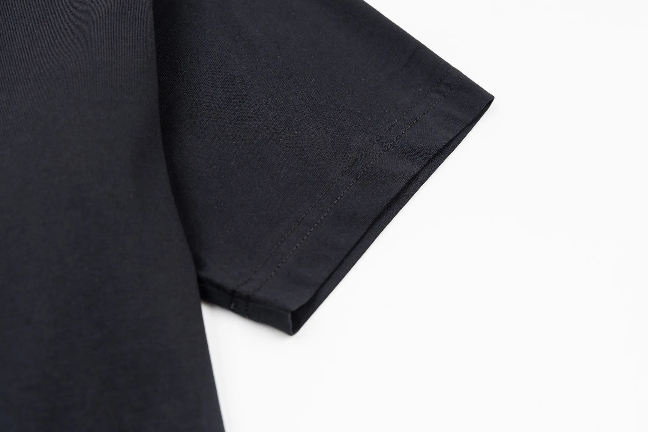 🅿️270 CD AND DESCENT Reflective Printed Short Sleeve (Black) The fabric is made of 24S 185g special woven compact cotton fabric, and the rib is made of 32S 300g double yarn rib. This T-shirt is a new product in the 2026 spring men's wear series, inspired by performance sportswear. Crafted from white cotton jersey with reflective ANDDESCENTE pattern. The ribbed round neck design can be layered with a zippered sweatshirt to create a sophisticated sporty look. The fabric is made of 24S special-spun compact cotton as a plain knitted base. The high-count compact spinning process ensures that the fabric has an extremely delicate skin feel and excellent anti-pilling durability. The neckline is equipped with 32S 1x1 high-density ribbing, which provides long-lasting rebound with its tight structure and protects the collar shape. It uses an advanced laser cutting reflective engraving film thermal transfer process: first, the composite reflective film with built-in micro glass beads is carved out by a high-precision laser cutting machine to create the precise outline of the words; the imprint is positioned and imprinted through precisely controlled temperature, pressure and time. It ensures the sharp and clear edges of the pattern and gives the item unique dynamic visual attributes. Under daily light, it presents a low-key silver-gray color, but when exposed to light in a dark place, it instantly bursts out with strong retroreflection. Through innovative reflective technology and sophisticated basic materials, performance is transformed into a perceptible visual language. Size:XS-S-M-L