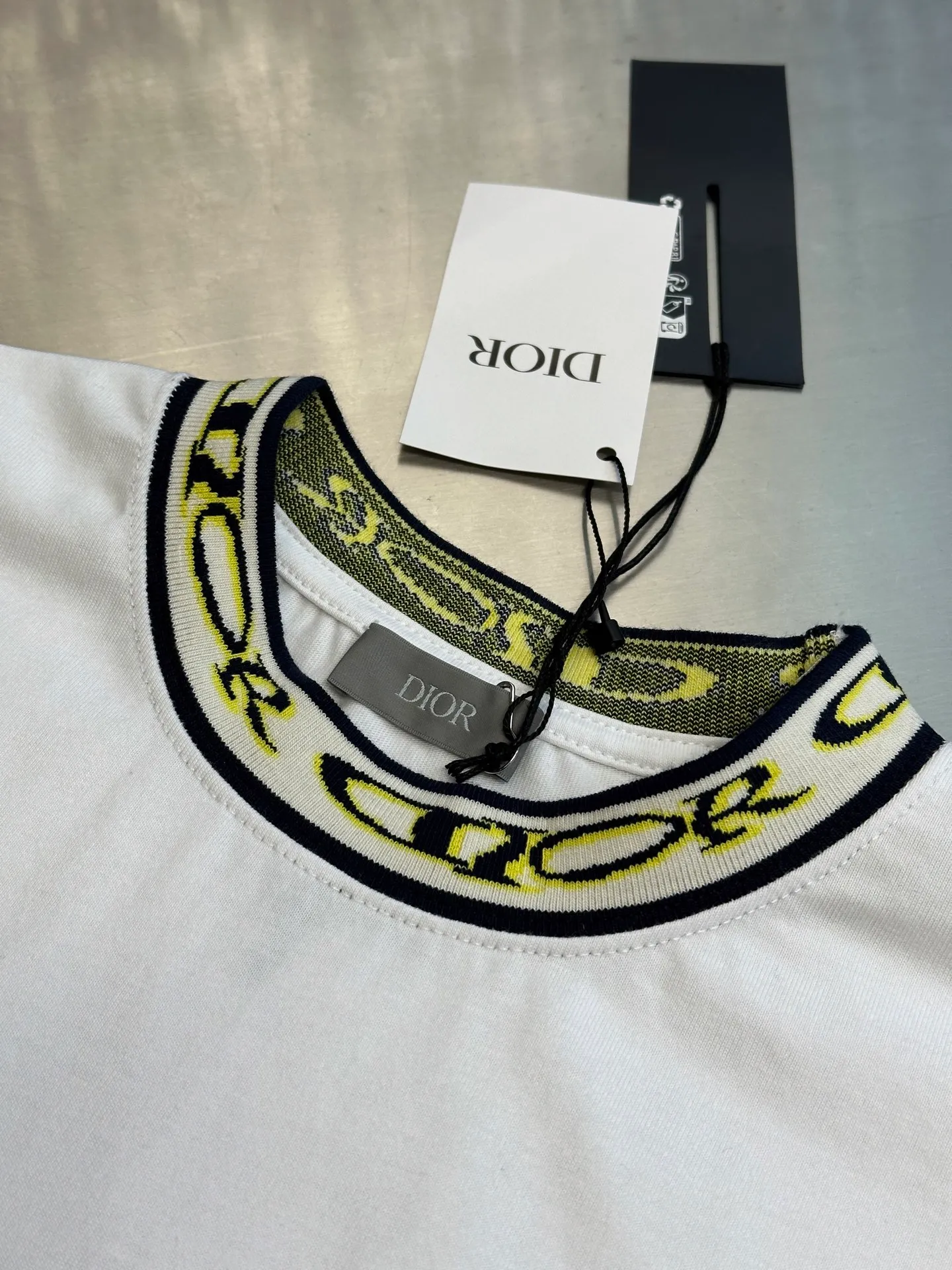 🅿️270 Dior artistic font rib short sleeves, cotton jersey fabric, made of 15S fine cotton plain weave, 230g; with threaded 32S double yarn rack, 300g. 15S is a relatively thick yarn used to make thicker and more durable fabrics. The fabric made of pure cotton natural fiber has the characteristics of good hygroscopicity, strong breathability, softness and comfort. Cotton fabrics are generally suitable for summer wear and can help keep your body dry and comfortable. The yarn passes alternately in the horizontal and vertical directions to form a simple cross structure; it has good elasticity and wear resistance.  The ribbed neckline is decorated with the joint series logo, the original artistic font is painted with flowers, and the flower collar pattern is woven with specific yarns of different colors. Fully computerized jacquard machine, the so-called computerized jacquard machine is to store the pattern data in a computer disk in advance, then put the disk into the computer of the loom, and the computer will control the weaving. The exquisite jacquard flat machine collar has clear and unique texture, rich color layers and is not easy to deform. Special double-layer weaving technology, rich color layering, strong three-dimensional jacquard effect on the surface, comfortable and skin-friendly, and good breathability.  The high-neck flat knit short-sleeved version and the round-neck short-sleeved T-shirt are restored in the design of the collar and cuffs, and special sewing methods or reinforcements are used to ensure the durability and comfort of these parts. Standard casual round neck short sleeves usually adopt a classic round neck design. The neckline is moderate in size, neither too tight nor too loose, and can well show the wearer's neck line.  size：xs s m l