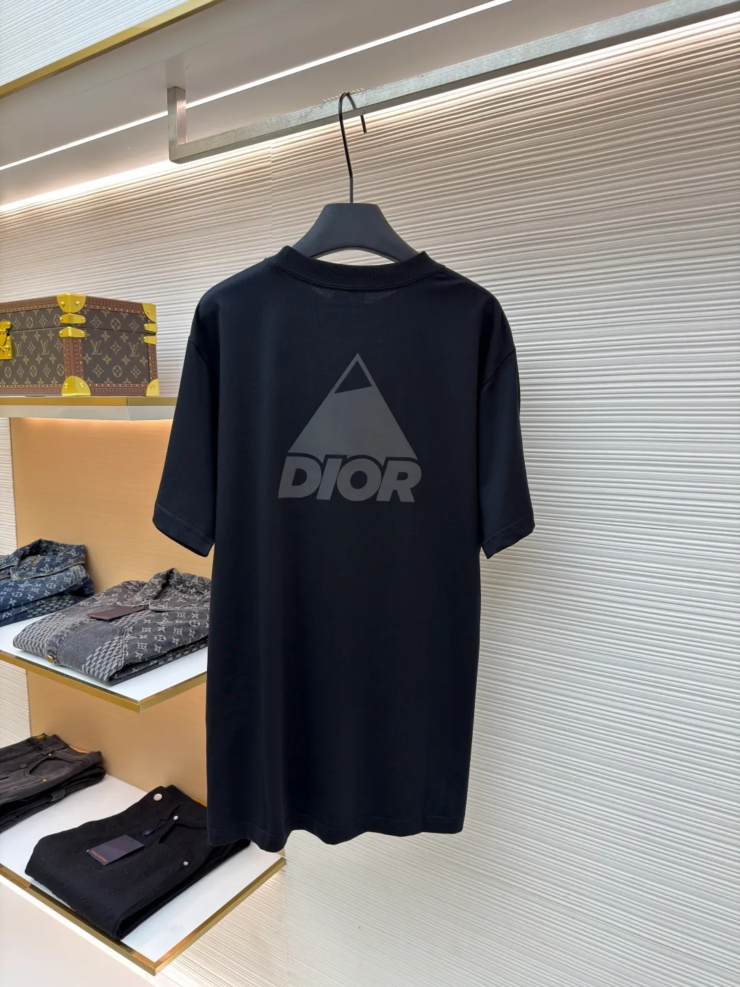 Dior Reflective Triangle Icon Round Neck Short Sleeve ●Original version: Purchased and developed by 6323 ●Item No.: 1681099-A00 ●Fabric: Jersey fabric ●Technology: Reflective lettering and embossed production ●Version: Fitted version ●Weight: about 220 grams ●Size: S-M-L-XL ●Description: The main body is made of 24S special woven compact cotton to make jersey fabric, weight 180g. High-count combed cotton yarn eliminates most of the short hairiness through compact spinning process, making the yarn smoother and stronger. The woven fabric structure is extremely dense, flat and soft, with excellent anti-pilling ability and durability, while retaining the natural advantages of pure cotton, which is breathable and skin-friendly. The neckline is made of 32S 1x1 rib with a weight of 300g. The finer yarn count creates a more delicate and tight thread, which provides better elasticity and deformation resistance than ordinary ribs, ensuring that the neckline can still remain stiff after being put on and taken off many times. The reflective engraving and embossing process is a sophisticated technology that combines safety functions with visual aesthetics. The core is to use a reflective lettering film with a built-in micro-glass bead layer. First, a high-precision laser cutting machine is used to engrave the outline according to the designed fonts and patterns to ensure that the edges are clear and burr-free. The cut reflective film is accurately attached to the surface of the fabric through heat transfer printing equipment under specific temperature and pressure, so that it is firmly combined with the fabric fibers. The case is matte silver-gray under normal conditions, but when illuminated by light, the micro-glass bead layer can achieve efficient retroreflection and instantly present a striking bright effect. The finished product is washable and abrasion resistant, perfectly meeting the dual needs of sportswear for functionality and visual tension. The overall wiring is straight and delicate, the fabric is comfortable and soft, and the color is consistent without color difference. It can be matched with the same style to create a fashionable look and control various occasions. Customized accessories, complete with three standards, same style for men and women!