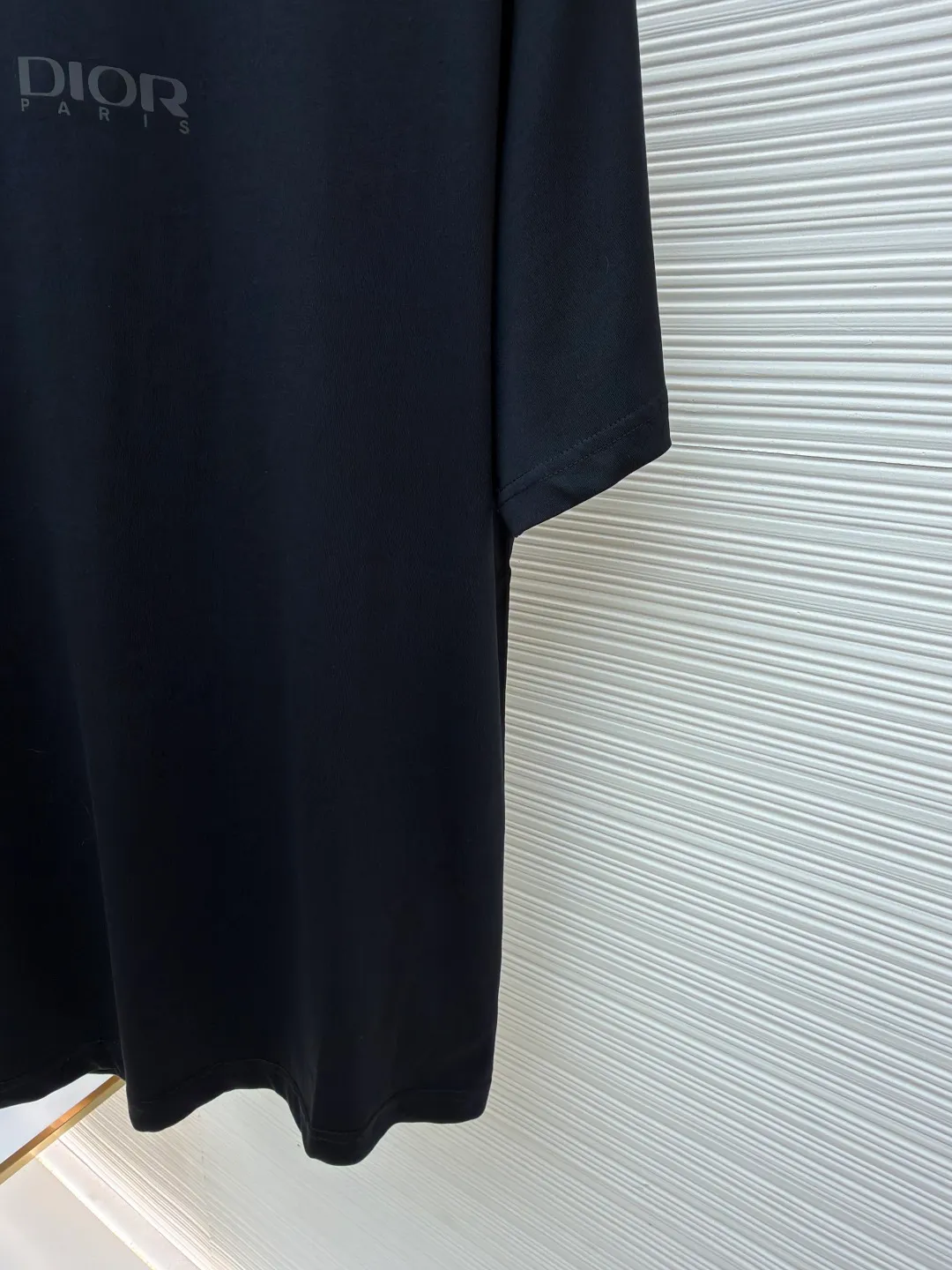 Dior Reflective Triangle Icon Round Neck Short Sleeve ●Original version: Purchased and developed by 6323 ●Item No.: 1681099-A00 ●Fabric: Jersey fabric ●Technology: Reflective lettering and embossed production ●Version: Fitted version ●Weight: about 220 grams ●Size: S-M-L-XL ●Description: The main body is made of 24S special woven compact cotton to make jersey fabric, weight 180g. High-count combed cotton yarn eliminates most of the short hairiness through compact spinning process, making the yarn smoother and stronger. The woven fabric structure is extremely dense, flat and soft, with excellent anti-pilling ability and durability, while retaining the natural advantages of pure cotton, which is breathable and skin-friendly. The neckline is made of 32S 1x1 rib with a weight of 300g. The finer yarn count creates a more delicate and tight thread, which provides better elasticity and deformation resistance than ordinary ribs, ensuring that the neckline can still remain stiff after being put on and taken off many times. The reflective engraving and embossing process is a sophisticated technology that combines safety functions with visual aesthetics. The core is to use a reflective lettering film with a built-in micro-glass bead layer. First, a high-precision laser cutting machine is used to engrave the outline according to the designed fonts and patterns to ensure that the edges are clear and burr-free. The cut reflective film is accurately attached to the surface of the fabric through heat transfer printing equipment under specific temperature and pressure, so that it is firmly combined with the fabric fibers. The case is matte silver-gray under normal conditions, but when illuminated by light, the micro-glass bead layer can achieve efficient retroreflection and instantly present a striking bright effect. The finished product is washable and abrasion resistant, perfectly meeting the dual needs of sportswear for functionality and visual tension. The overall wiring is straight and delicate, the fabric is comfortable and soft, and the color is consistent without color difference. It can be matched with the same style to create a fashionable look and control various occasions. Customized accessories, complete with three standards, same style for men and women!