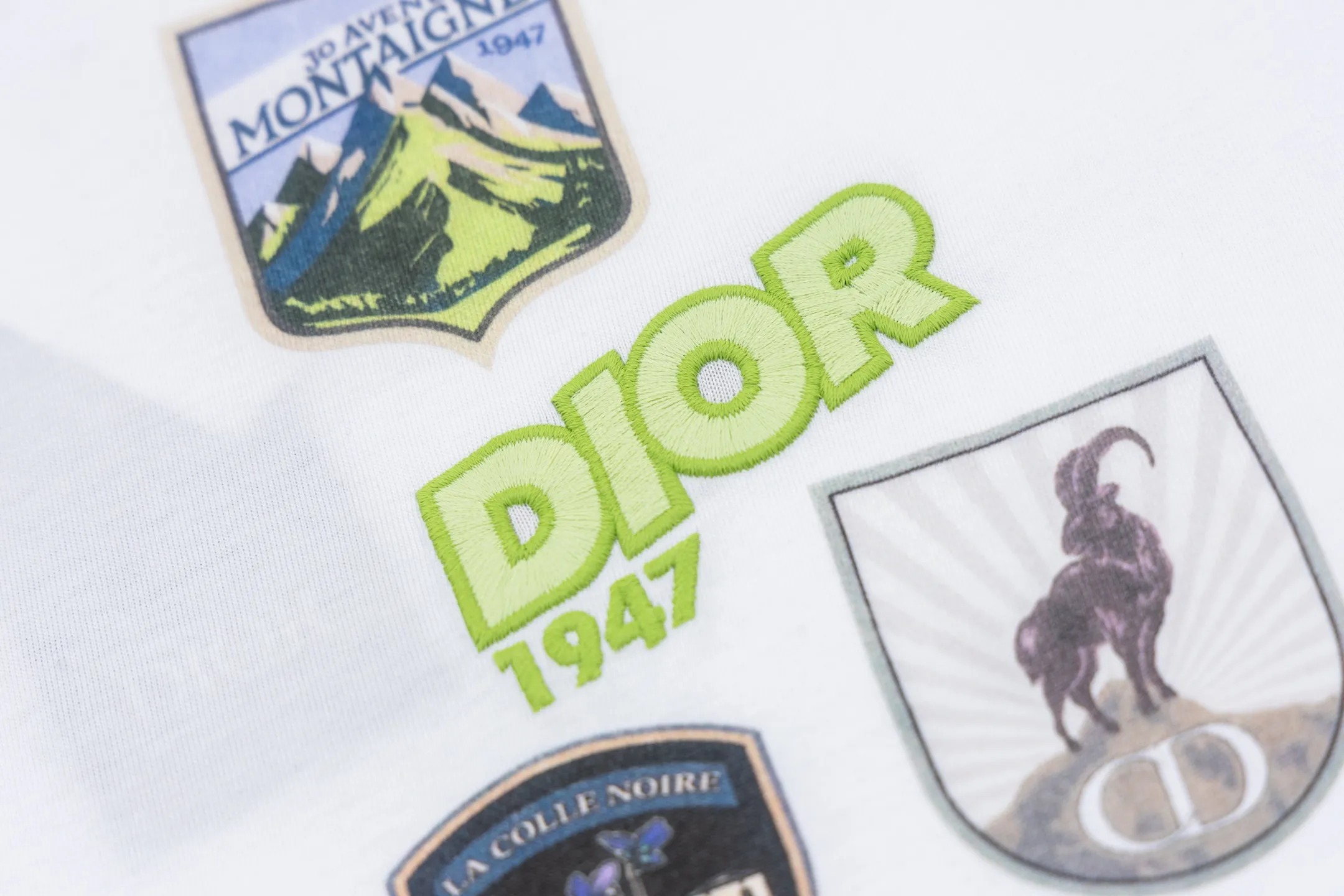 🅿️280 CD Mountain Alpine Shield Printed Short Sleeve (White) The fabric is made of 24S 185g special woven compact cotton fabric, and the rib is made of 32S 300g double yarn rib. This Mountain T-shirt is a new product of the 2026 spring men's wear series. It is decorated with multi-color patches to show the mountain spirit and the classic logo of high-end style inspired by archives. Crafted from white cotton jersey, it features a crew neck for a refined look. The fabric is made of 24S special-spun compact cotton as a plain knitted base. The high-count compact spinning process ensures that the fabric has an extremely delicate skin feel and excellent anti-pilling durability. The neckline is equipped with 32S 1x1 high-density ribbing, which provides long-lasting rebound with its tight structure and protects the collar shape. The decorative multi-color embroidery patch adopts appliqué technique. Three-dimensional lines and fluorescent details are first embroidered with high-density stitches on independent fabrics, and then accurately covered on the chest, forming a strong visual hierarchy and tactile contrast. The alpine element pattern uses digital white ink direct injection technology, with saturated colors and sharp edges, which together with the embroidery patch create a rich texture. Size:XS-S-M-L