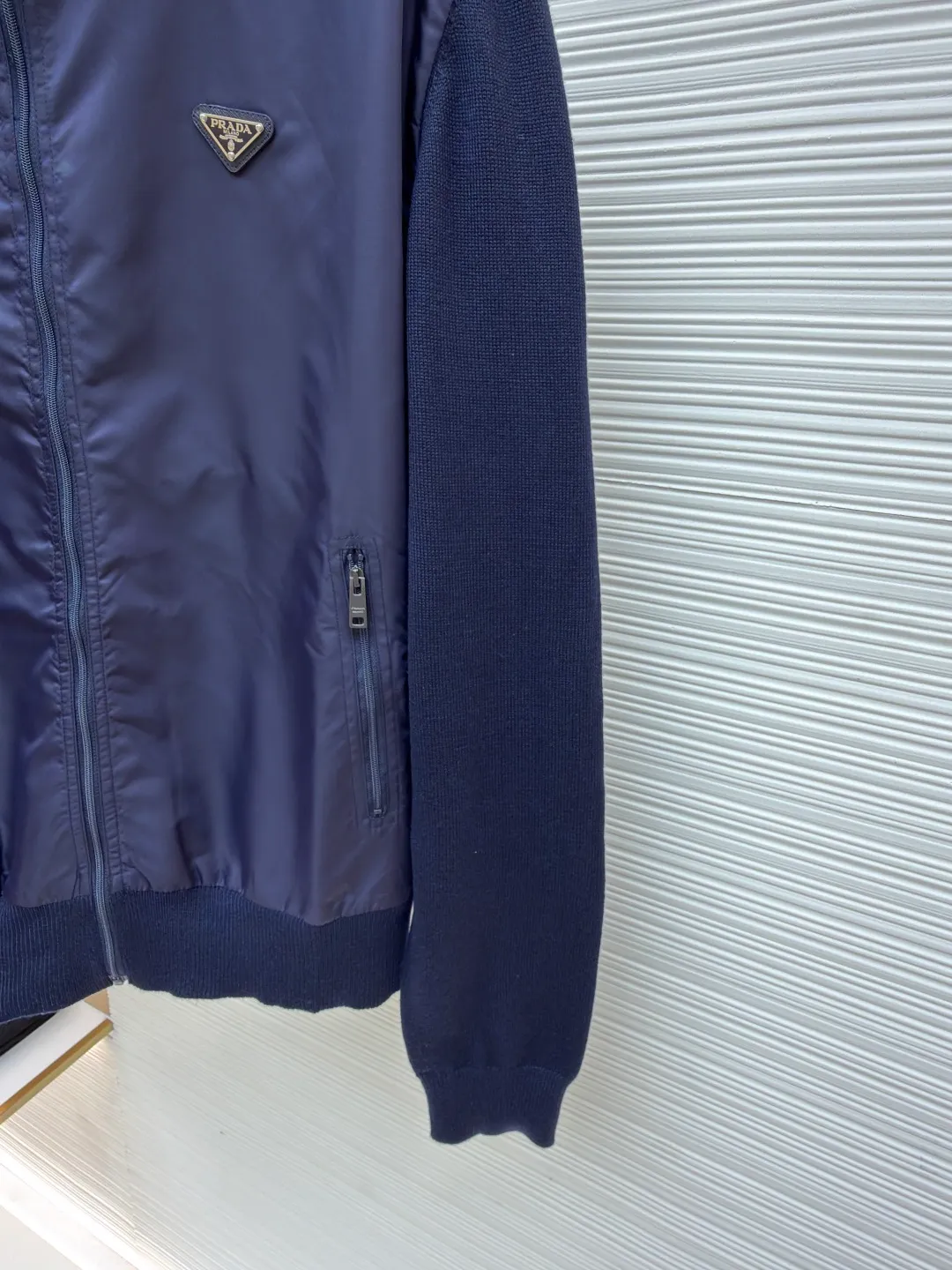Prada triangle logo knitted splicing nylon jacket ●Original version: Purchased and developed at 20800 ●Item number: 1681157-B40 ●Fabric: twill light-sensitive nylon laminated fabric ●Technology: made with garment wash ●Color: dark blue ●Version: fitted version ●Weight: about 505 grams ●Size: 48-50-52-54 ●Description: Customized twill light-sensitive nylon laminated material And custom-woven mercerized wool blended knitted fabric, soft and delicate, comfortable and close to the skin. Using deep navy blue as the ink and splicing as the pen, harmonious symbiosis. The iconic enameled triangular metal logo is embellished to highlight the elegance and nobility of the brand. Use splicing design to deconstruct classics. When the gentleness of wool meets the sharpness of Re-Nylon, it reveals a flexible and relaxed beauty. The tactile layering is the ultimate sense of luxury. It is a detail hidden in the restraint. The infrared positioning of the "Prada triangle mark" by an imported special machine is more precise and firm. Seamless splicing is made with fine workmanship. The sweater fabric pieces are connected together through specific sewing and knitting techniques, so that there are almost no traces of the splicing. The splicing effect is beautiful and neat, and the template machine opens the bag. The preset template guides the position, shape and size of the bag opening. The accuracy ensures the quality of the bag opening effect. The ready-to-wear washing water is softened and deodorized through professional washing equipment and specific detergents. The clothes are deeply cleaned and deodorized to improve the feel and appearance of the clothes. The overall wiring is straight and delicate, the fabric is comfortable and soft, and the color is consistent without color difference. It can be matched with the same style to create a fashionable look and control various occasions. Customized accessories, complete with three standards, same style for men and women!