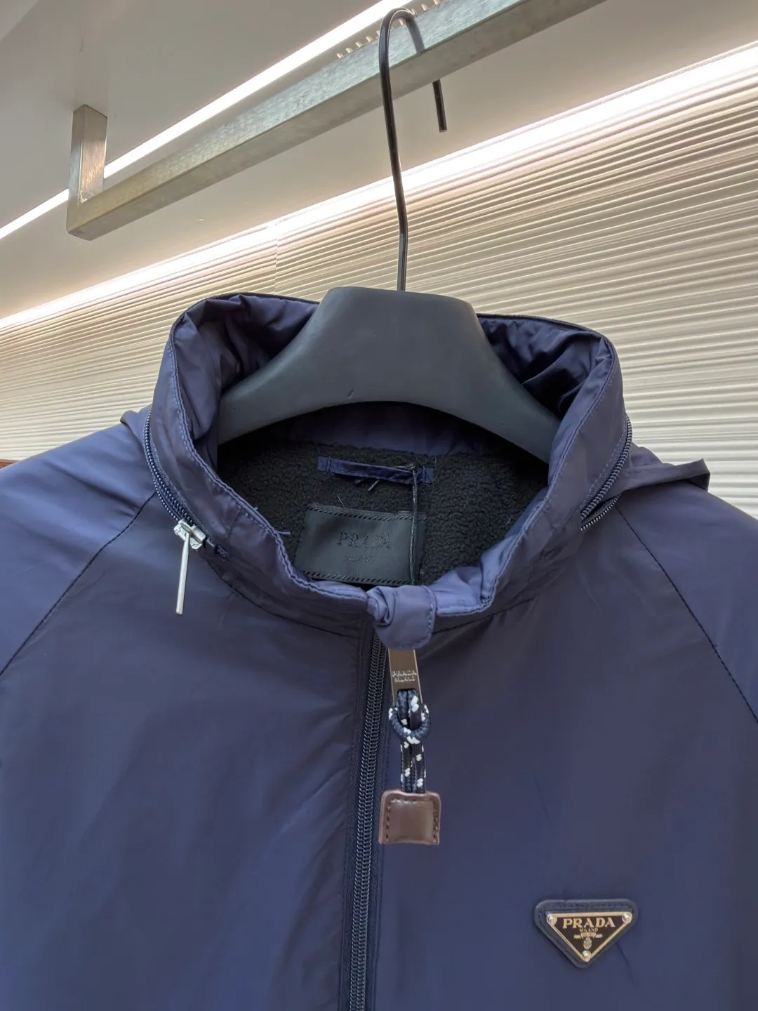 Prada Regenerated Nylon Fleece Jacket ●Original version: Purchased and developed by 12048 ●Item number: 1682331-B70 ●Fabric: Regenerated nylon fabric ●Technology: Made on positioning cutting machine ●Color: Navy blue ●Version: Fitted version ●Weight: about 585 grams ●Size: S-M-L-XL ●Description: High-density yarn is made by melt spinning through a special process. The yarn has been stretched and twisted through multiple processes to give the fabric the stiffness and wrinkle resistance that are comparable to those of native materials, while retaining a light and drapey wearing experience. The surface of the fabric is treated with an environmentally friendly coating process to form a micro-waterproof film layer, which is both windproof and breathable. The main raw material is polyester fiber blended wool raw material which is cleaned and pre-treated to remove impurities. After the yarn is woven into fabric through a loom, it is brushed, that is, the surface of the fiber is fluffed through mechanical brushing to form fluff. Then the shaking process is carried out, and the fabric is shaken under high temperature and humid conditions, so that the fibers form small spherical particles to increase the thermal insulation performance. The shoulder splicing uses twill sewing technology, the raglan sleeve design releases shoulder movement space, and the regular shoulder line ensures the stiffness of the overall silhouette, maintaining an elegant silhouette for both sports and static wear. The three-dimensional pleat design is incorporated into both sides of the body and sleeve elbows, and a long-lasting pleat texture is formed through high-temperature setting technology. This not only enhances the aerodynamic performance of the fabric, but also enriches the visual hierarchy with light and shadow changes, breaking the dull feeling of solid color fabrics. The cuffs are equipped with a hidden snap-button adjustment system, which can be freely tightened according to the circumference of the wrist to prevent cold wind from entering; the straight bottom edge is matched with a drawstring at the hem, and the inner rope buckle design can be used to adjust the tightness, taking into account warmth preservation and waistline shaping. The overall wiring is straight and delicate, the fabric is comfortable and soft, and the color is consistent without color difference. It can be matched with the same style to create a fashionable look and control various occasions. Customized accessories, complete with three standards, same style for men and women!