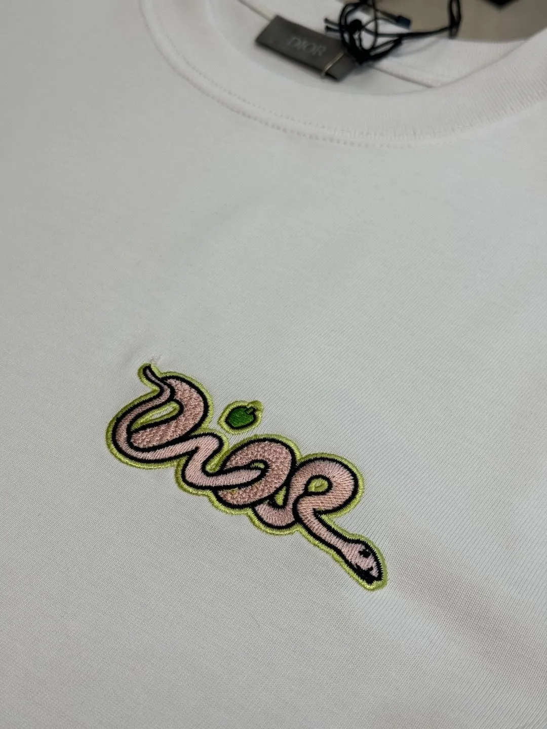 🅿️280 Dior Apple Snake Embroidered Chapter Short Sleeve Made of pure cotton 12S fine cotton plain fabric, 310g. The embroidery pattern is based on tatami embroidery technology. The embroidery uses a special single-needle arrangement. The stitches are tight and flat, forming a texture similar to the tatami grid, making the embroidery pattern have a strong three-dimensional and layered feel. Embroidered with silk threads of multiple colors, the colors are bright and contrasting, showing rich patterns and details.  The outline is stroked by needle embroidery, the embroidery pattern is matched with the brand logo design, and the brand letter logo is single-needle flat embroidered. Made from a variety of needlework; the outline of the pattern is embroidered with a single straight line and straight silk thread. The outline edges and letter embroidery are stitched together to create clear and rich three-dimensional layers.  The standard round neck and short-sleeved version has a rounded arc neckline, which is suitable for various face shapes and body shapes; the sleeve length is moderate and ends just above the elbow, showing a smart and neat image. The slim fit can show off the wearer's body curves without sacrificing comfort. The collar, cuffs, hem and other parts are all sewn with fine double-needle stitching.  size：xs s m l