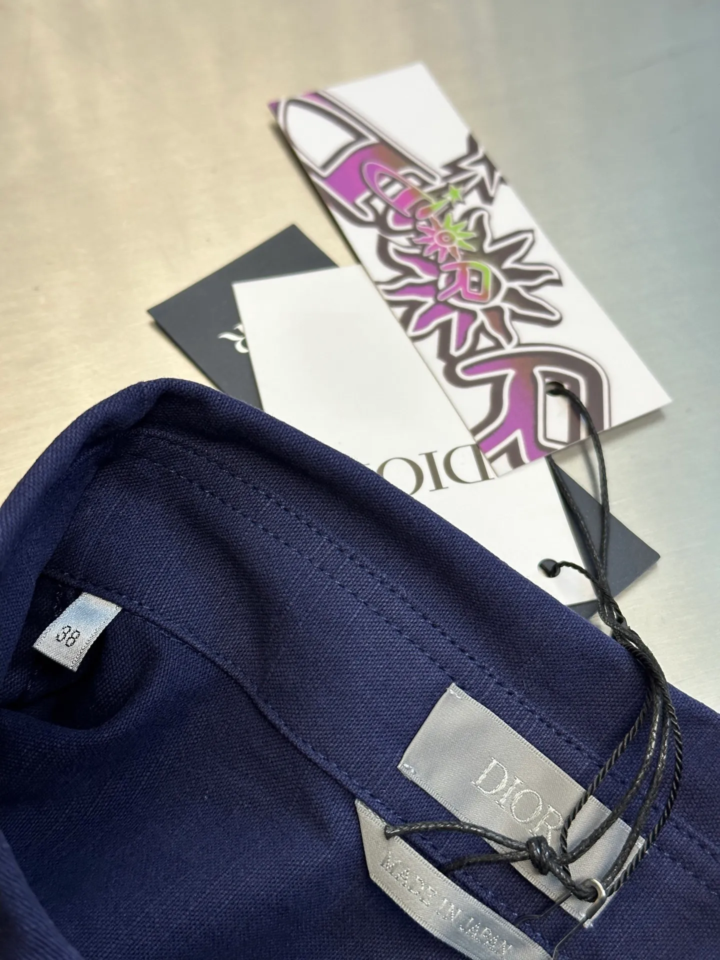 🅿️490 Dior LEWIS HAMILTON Curtain Call Shirt Crafted from blue cotton, it is decorated with patch pockets on the chest, one of which is embellished with tonal co-branded embroidery, reinterpreting the logo in a graphic style. Pair with shorts from the limited collection for a refined look.  Chambray is made of plain weave, which is characterized by interweaving yarn materials of different colors in the warp and weft. It can reflect different levels of light and shade under different light angles, and the colors are rich in changes. The cloth is light and thin in texture, smooth and soft in body, and comfortable to wear. After a specific finishing process, its elasticity and feel are further improved.  Flat stitch embroidery three-dimensional craft is a special embroidery technique that uses flat stitch to create embroidery with a three-dimensional feel. This process creates a richer three-dimensional effect and layering by precisely controlling the depth and angle of the stitches and increasing the density and length.  size:36.38.40.42