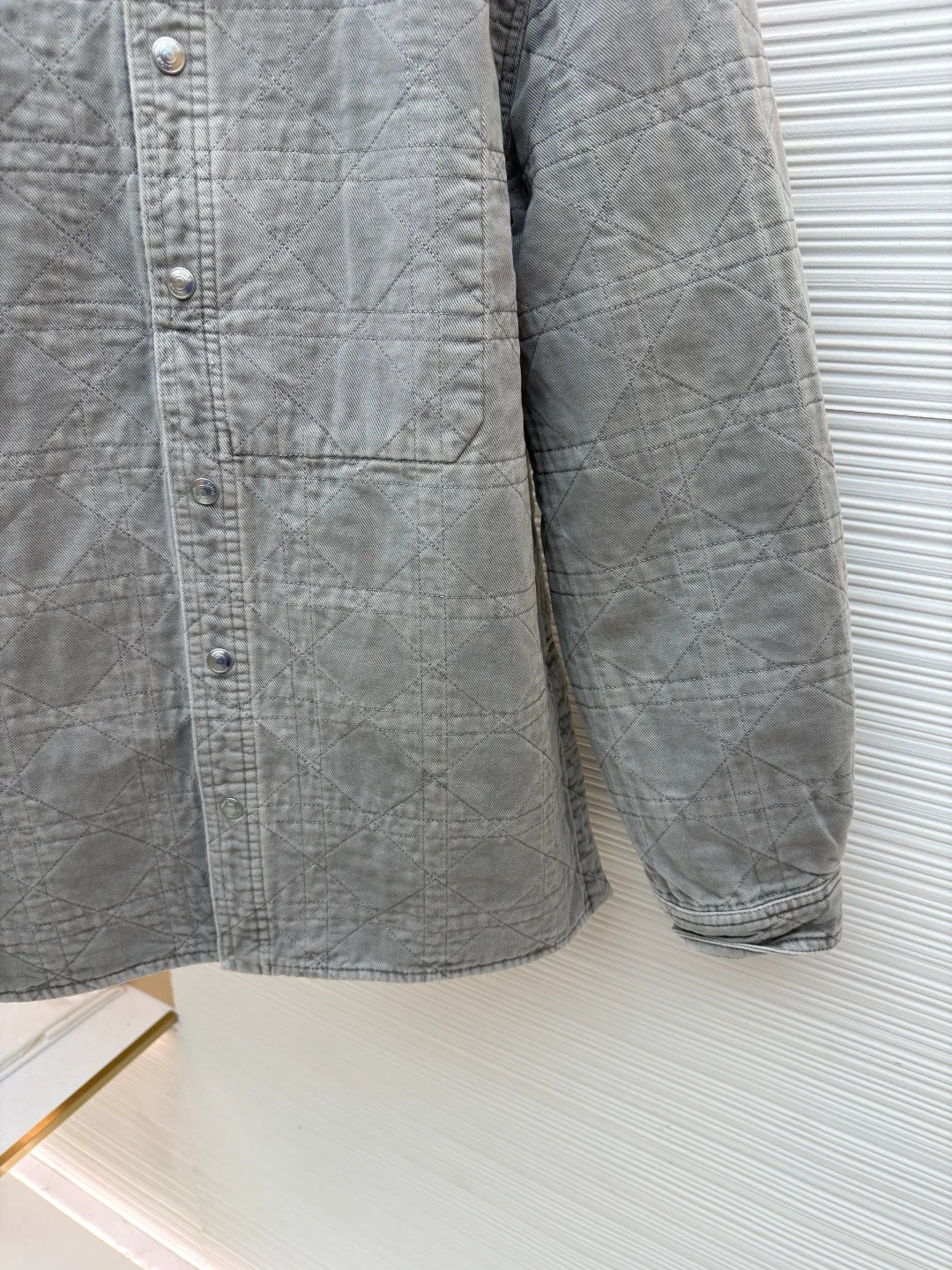Dior cotton twill cannage pattern embroidered lapel single-breasted long-sleeved shirt ●Original version: purchased and developed by 17011 ●Item number: 1682544-C45 ●Material: cotton twill fabric ●Technology: embroidery production ●Color: gray ●Version: fitted version ●Weight: about 1045 grams ●Size: 46-48-50-52-54-56 ●Description: This quilted shirt-style jacket is made of high-weight cotton twill fabric. It has been stone-washed and enzyme-washed to give it a light gray distressed texture. The fabric is soft and skin-friendly, yet stiff and resistant to deformation and fading. The body of the garment adopts rhombus quilting technology, the stitching is even and regular, and the thin cotton filling is densely distributed, giving both warmth and breathability, and preventing cotton batting from clumping and moving around. The classic shirt lapel design is neat and elegant, the custom-made metal snaps at the placket are smooth and durable, the cuffs are adjustable sleeves, the shoulders are seamlessly spliced, and the hem is straight and fine. The overall cut is an oversized and loose silhouette, with complete customized accessories and detailed craftsmanship to show the avant-garde street style. It can be worn alone or layered, and is suitable for various wearing scenarios such as daily outings and casual commuting. The overall wiring is straight and delicate, the fabric is comfortable and soft, and the color is consistent without color difference. It can be matched with the same style to create a fashionable look and control various occasions. Customized accessories, complete with three standards, same style for men and women!