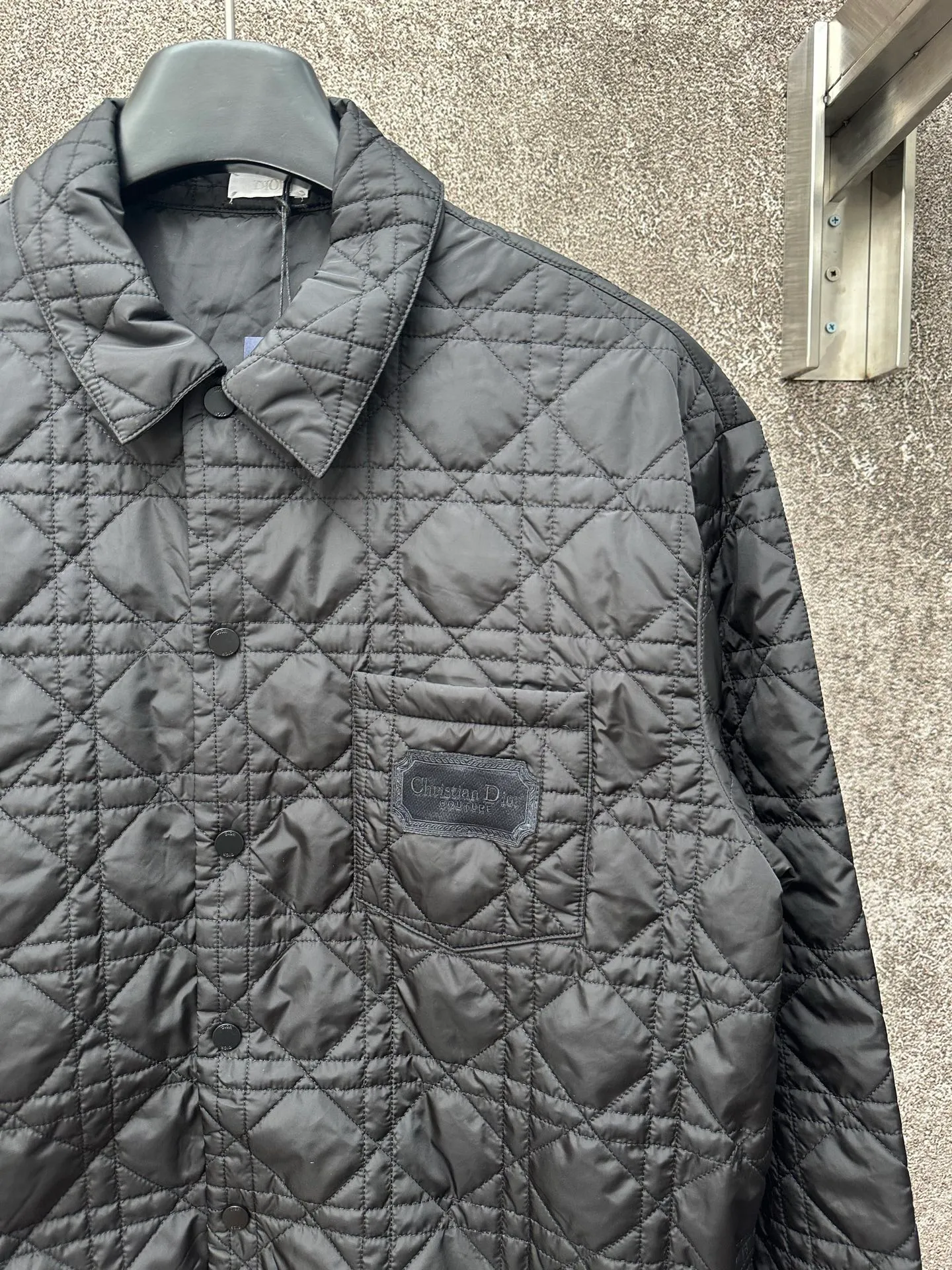 🅿️550 Dior 25ss new jacket shirt reinterprets the classic design and highlights modern style. Crafted from black technical fabric for a sleek silhouette, it's finished with a classic tonal quilted cannage pattern throughout. The chest patch pocket is decorated with +Christian+Dior+Couture+ embroidery, and the side slits are designed with snap buttons and can be worn open or buttoned. Blending traditional and modern styles, pair it with jeans or shorts for a sophisticated, stylish look.  Size: S M L XL