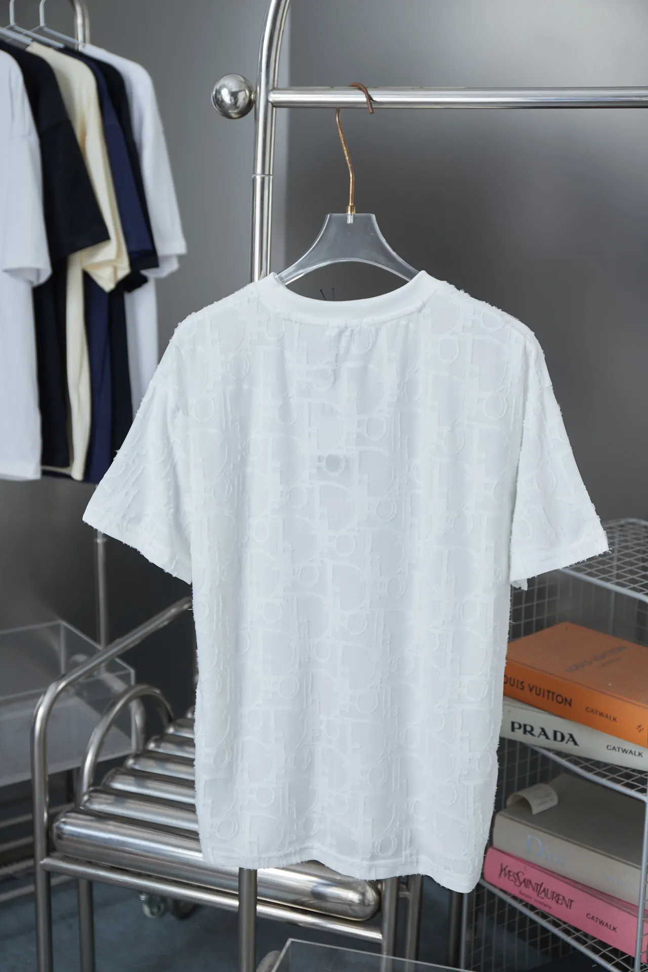 🅿️180 Dior 2025 new style embossed jacquard short-sleeved pure cotton plain fabric, woven with 32S double-strand pure cotton yarn. The 32S double-strand is twisted from two 32-count single yarns. The yarn is thicker and stronger. The fabric has high wear resistance while retaining the moisture absorption and breathability of pure cotton. The plain weave has a tight structure and a smooth surface, but it feels relatively stiff and supports the stiffness of the pattern. The jacquard pattern uses thread-cutting jacquard technology, and the full-width Oblique jacquard pattern forms a relief effect through the deep integration of full-width jacquard and shearing technology. The jacquard structure provides a three-dimensional frame, and the shearing process enhances local texture. The electronic jacquard machine is used to weave complex patterns on the entire fabric to form a three-dimensional concave and convex texture, achieving the integration of texture and pattern. The raised jacquard is cut in a directional manner to create a relief effect, enhancing tactile layering and visual contrast. Straight crew neck fit. Cut and sewn in floral position, standard H hanging fit, with shoulder-length design. The vertical version emphasizes that the width of the shoulders, waist, and hem are basically the same, and it is simple and loose. The short sleeves are tailored to fit the body of the wearer. At the same time, the neckline, cuffs and hem of the short sleeves are all designed with double lines. S M L XL