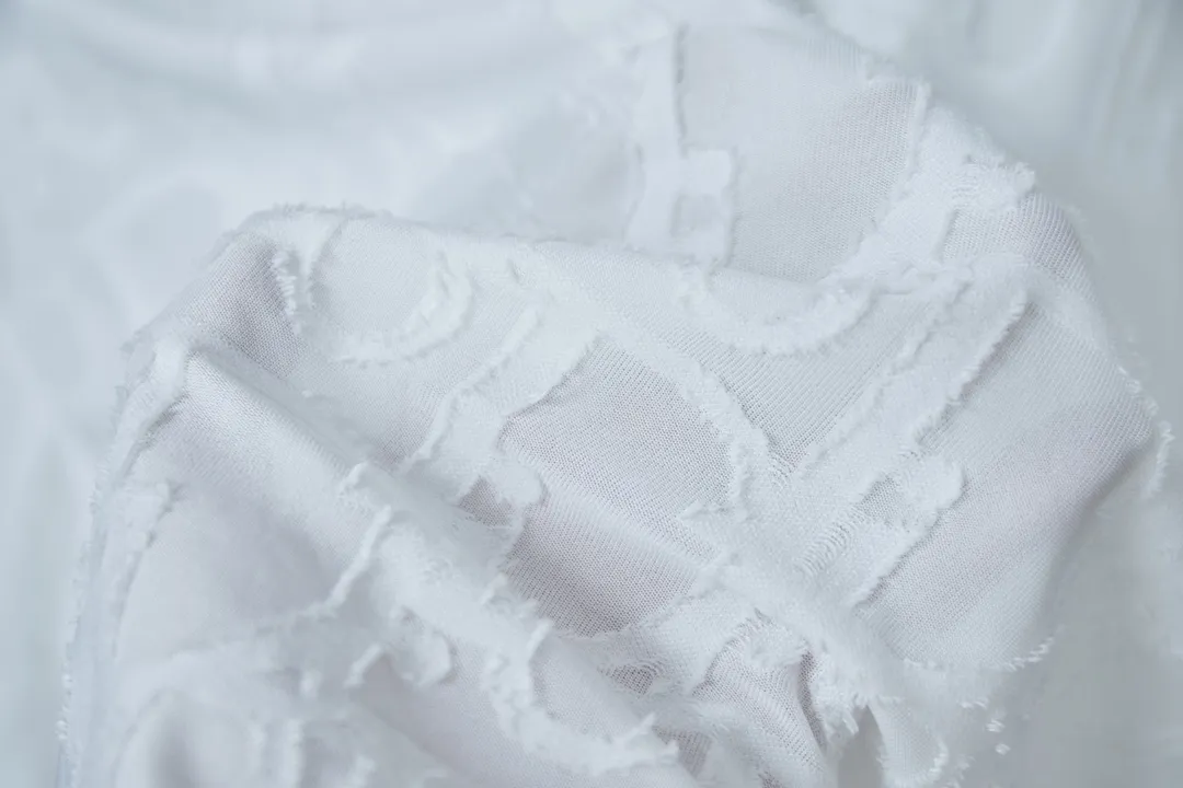 🅿️180 Dior 2025 new style embossed jacquard short-sleeved pure cotton plain fabric, woven with 32S double-strand pure cotton yarn. The 32S double-strand is twisted from two 32-count single yarns. The yarn is thicker and stronger. The fabric has high wear resistance while retaining the moisture absorption and breathability of pure cotton. The plain weave has a tight structure and a smooth surface, but it feels relatively stiff and supports the stiffness of the pattern. The jacquard pattern uses thread-cutting jacquard technology, and the full-width Oblique jacquard pattern forms a relief effect through the deep integration of full-width jacquard and shearing technology. The jacquard structure provides a three-dimensional frame, and the shearing process enhances local texture. The electronic jacquard machine is used to weave complex patterns on the entire fabric to form a three-dimensional concave and convex texture, achieving the integration of texture and pattern. The raised jacquard is cut in a directional manner to create a relief effect, enhancing tactile layering and visual contrast. Straight crew neck fit. Cut and sewn in floral position, standard H hanging fit, with shoulder-length design. The vertical version emphasizes that the width of the shoulders, waist, and hem are basically the same, and it is simple and loose. The short sleeves are tailored to fit the body of the wearer. At the same time, the neckline, cuffs and hem of the short sleeves are all designed with double lines. S M L XL
