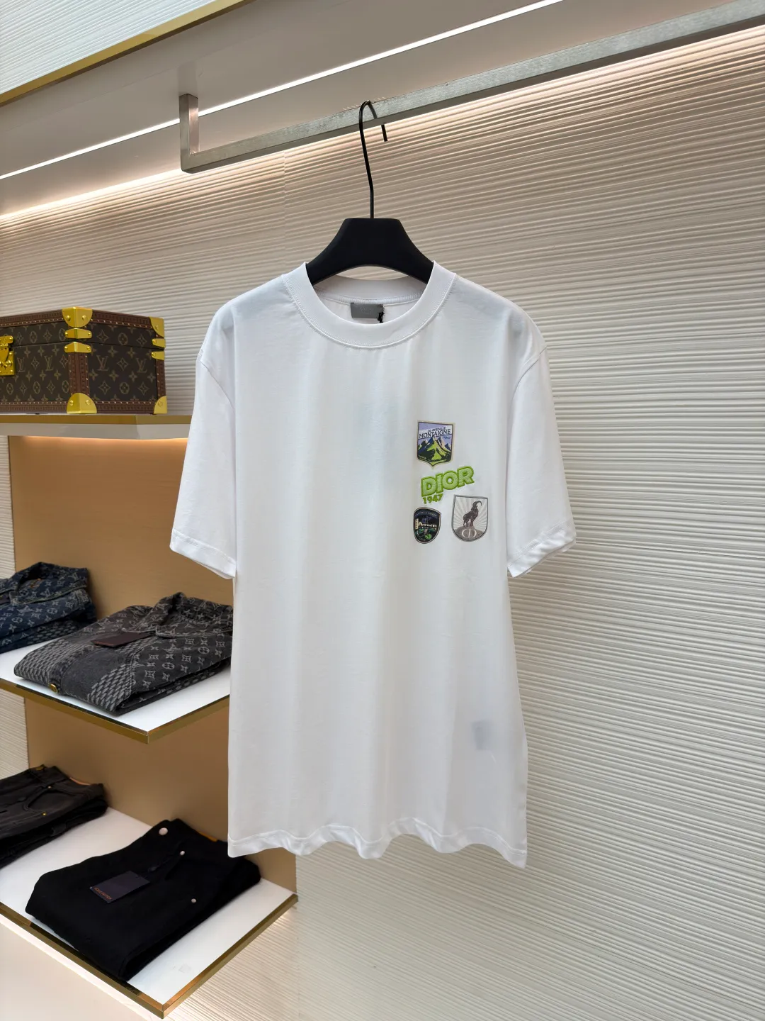 Dior Alpine Embroidery Round Neck Short Sleeve ●Original version: Purchased and developed by 7149 ●Item number: 1681102-A05 ●Fabric: plain knitted fabric ●Technology: White ink direct injection production ●Version: Fitted version ●Weight: about 200 grams ●Size: XS-S-M-L ●Description: The main body is made of 24S special woven compact cotton to make plain knitted fabric, weight 180g. High-count combed cotton yarn eliminates most of the short hairiness through compact spinning process, making the yarn smoother and stronger. The woven fabric structure is extremely dense, flat and soft, with excellent anti-pilling ability and durability, while retaining the natural advantages of pure cotton, which is breathable and skin-friendly. The neckline is made of 32S 1x1 rib with a weight of 300g. The finer yarn count creates a more delicate and tight thread, which provides better elasticity and deformation resistance than ordinary ribs, ensuring that the neckline can still remain stiff after being put on and taken off many times. The printed pattern and classic logo inspired by the mountain spirit on the chest become the visual focus through the decoration combined with multiple techniques. The printed pattern elements use digital white ink direct injection technology, which presents bright, opaque white and color patterns on dark fabrics with clear edges and a smooth touch. The classic logo is completed with fluorescent green contrasting letters in the form of patches, which are then precisely sewn onto the fabric using appliqué technology. This process restores the three-dimensionality, color saturation and detail accuracy of the pattern to the original version. With the standard round neck shape and basic color, this product has established a high degree of matching tolerance. It can be mixed and matched with daily jeans or shorts, catering to the pursuit of functionality, comfort and details. The neckline has a rounded arc, suitable for various face shapes and body shapes; the sleeves are moderate and end just above the elbow, showing a smart and neat image. The slim-fitting cut shows off the wearer's body curves without sacrificing comfort. The collar, cuffs, hem and other parts are all sewn with fine double-needle stitching. The overall wiring is straight and delicate, the fabric is comfortable and soft, and the color is consistent without color difference. It can be matched with the same style to create a fashionable look and control various occasions. Customized accessories, complete with three standards, same style for men and women!
