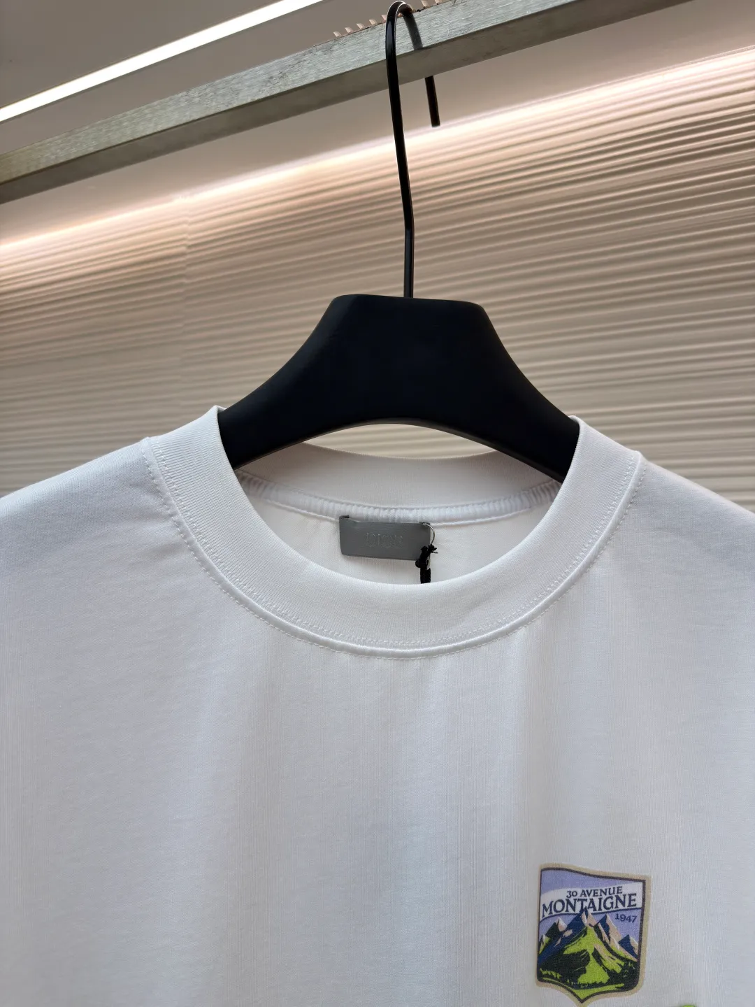 Dior Alpine Embroidery Round Neck Short Sleeve ●Original version: Purchased and developed by 7149 ●Item number: 1681102-A05 ●Fabric: plain knitted fabric ●Technology: White ink direct injection production ●Version: Fitted version ●Weight: about 200 grams ●Size: XS-S-M-L ●Description: The main body is made of 24S special woven compact cotton to make plain knitted fabric, weight 180g. High-count combed cotton yarn eliminates most of the short hairiness through compact spinning process, making the yarn smoother and stronger. The woven fabric structure is extremely dense, flat and soft, with excellent anti-pilling ability and durability, while retaining the natural advantages of pure cotton, which is breathable and skin-friendly. The neckline is made of 32S 1x1 rib with a weight of 300g. The finer yarn count creates a more delicate and tight thread, which provides better elasticity and deformation resistance than ordinary ribs, ensuring that the neckline can still remain stiff after being put on and taken off many times. The printed pattern and classic logo inspired by the mountain spirit on the chest become the visual focus through the decoration combined with multiple techniques. The printed pattern elements use digital white ink direct injection technology, which presents bright, opaque white and color patterns on dark fabrics with clear edges and a smooth touch. The classic logo is completed with fluorescent green contrasting letters in the form of patches, which are then precisely sewn onto the fabric using appliqué technology. This process restores the three-dimensionality, color saturation and detail accuracy of the pattern to the original version. With the standard round neck shape and basic color, this product has established a high degree of matching tolerance. It can be mixed and matched with daily jeans or shorts, catering to the pursuit of functionality, comfort and details. The neckline has a rounded arc, suitable for various face shapes and body shapes; the sleeves are moderate and end just above the elbow, showing a smart and neat image. The slim-fitting cut shows off the wearer's body curves without sacrificing comfort. The collar, cuffs, hem and other parts are all sewn with fine double-needle stitching. The overall wiring is straight and delicate, the fabric is comfortable and soft, and the color is consistent without color difference. It can be matched with the same style to create a fashionable look and control various occasions. Customized accessories, complete with three standards, same style for men and women!