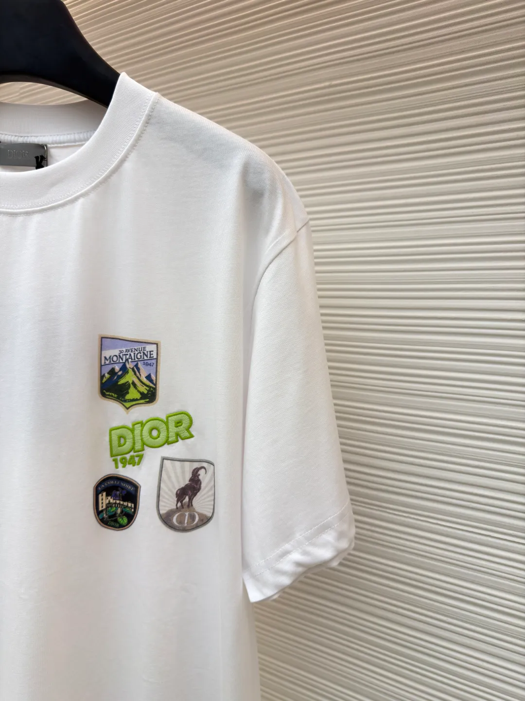 Dior Alpine Embroidery Round Neck Short Sleeve ●Original version: Purchased and developed by 7149 ●Item number: 1681102-A05 ●Fabric: plain knitted fabric ●Technology: White ink direct injection production ●Version: Fitted version ●Weight: about 200 grams ●Size: XS-S-M-L ●Description: The main body is made of 24S special woven compact cotton to make plain knitted fabric, weight 180g. High-count combed cotton yarn eliminates most of the short hairiness through compact spinning process, making the yarn smoother and stronger. The woven fabric structure is extremely dense, flat and soft, with excellent anti-pilling ability and durability, while retaining the natural advantages of pure cotton, which is breathable and skin-friendly. The neckline is made of 32S 1x1 rib with a weight of 300g. The finer yarn count creates a more delicate and tight thread, which provides better elasticity and deformation resistance than ordinary ribs, ensuring that the neckline can still remain stiff after being put on and taken off many times. The printed pattern and classic logo inspired by the mountain spirit on the chest become the visual focus through the decoration combined with multiple techniques. The printed pattern elements use digital white ink direct injection technology, which presents bright, opaque white and color patterns on dark fabrics with clear edges and a smooth touch. The classic logo is completed with fluorescent green contrasting letters in the form of patches, which are then precisely sewn onto the fabric using appliqué technology. This process restores the three-dimensionality, color saturation and detail accuracy of the pattern to the original version. With the standard round neck shape and basic color, this product has established a high degree of matching tolerance. It can be mixed and matched with daily jeans or shorts, catering to the pursuit of functionality, comfort and details. The neckline has a rounded arc, suitable for various face shapes and body shapes; the sleeves are moderate and end just above the elbow, showing a smart and neat image. The slim-fitting cut shows off the wearer's body curves without sacrificing comfort. The collar, cuffs, hem and other parts are all sewn with fine double-needle stitching. The overall wiring is straight and delicate, the fabric is comfortable and soft, and the color is consistent without color difference. It can be matched with the same style to create a fashionable look and control various occasions. Customized accessories, complete with three standards, same style for men and women!