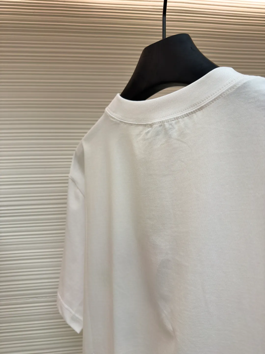 Dior Alpine Embroidery Round Neck Short Sleeve ●Original version: Purchased and developed by 7149 ●Item number: 1681102-A05 ●Fabric: plain knitted fabric ●Technology: White ink direct injection production ●Version: Fitted version ●Weight: about 200 grams ●Size: XS-S-M-L ●Description: The main body is made of 24S special woven compact cotton to make plain knitted fabric, weight 180g. High-count combed cotton yarn eliminates most of the short hairiness through compact spinning process, making the yarn smoother and stronger. The woven fabric structure is extremely dense, flat and soft, with excellent anti-pilling ability and durability, while retaining the natural advantages of pure cotton, which is breathable and skin-friendly. The neckline is made of 32S 1x1 rib with a weight of 300g. The finer yarn count creates a more delicate and tight thread, which provides better elasticity and deformation resistance than ordinary ribs, ensuring that the neckline can still remain stiff after being put on and taken off many times. The printed pattern and classic logo inspired by the mountain spirit on the chest become the visual focus through the decoration combined with multiple techniques. The printed pattern elements use digital white ink direct injection technology, which presents bright, opaque white and color patterns on dark fabrics with clear edges and a smooth touch. The classic logo is completed with fluorescent green contrasting letters in the form of patches, which are then precisely sewn onto the fabric using appliqué technology. This process restores the three-dimensionality, color saturation and detail accuracy of the pattern to the original version. With the standard round neck shape and basic color, this product has established a high degree of matching tolerance. It can be mixed and matched with daily jeans or shorts, catering to the pursuit of functionality, comfort and details. The neckline has a rounded arc, suitable for various face shapes and body shapes; the sleeves are moderate and end just above the elbow, showing a smart and neat image. The slim-fitting cut shows off the wearer's body curves without sacrificing comfort. The collar, cuffs, hem and other parts are all sewn with fine double-needle stitching. The overall wiring is straight and delicate, the fabric is comfortable and soft, and the color is consistent without color difference. It can be matched with the same style to create a fashionable look and control various occasions. Customized accessories, complete with three standards, same style for men and women!