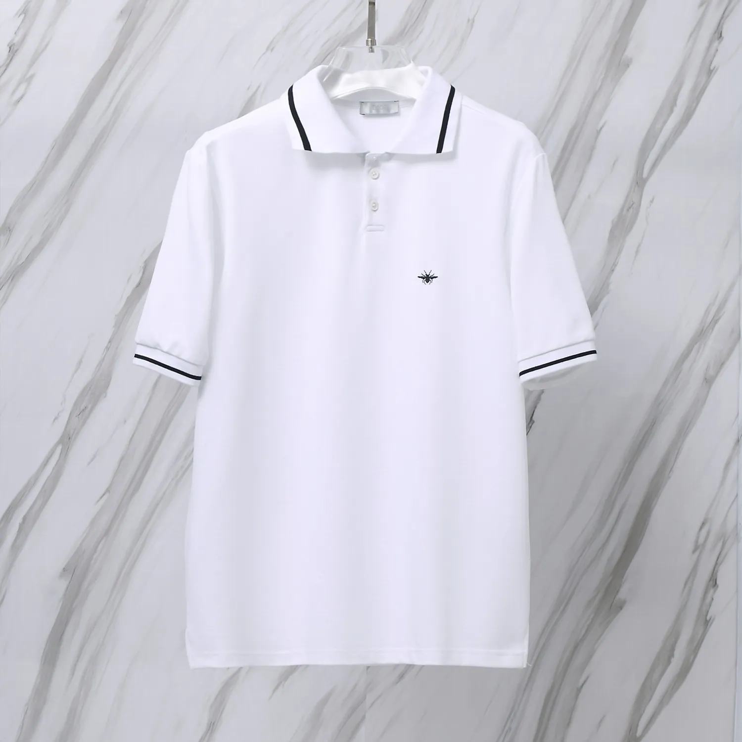 🅿️190 Item No. D41 (Dior classic little bee logo embroidered POLO shirt) Dior Dior 24ss new little bee letter embroidered logo lapel polo shirt short-sleeved T-shirt. The counter restores the top replica for men and women. The own factory style is very good, business commuting, classic POLO lapel design, classic small logo embroidery design on the chest highlights personality, making the entire line smoother, the most classic evergreen small logo design Exquisite embroidered logo design on the chest, pure cotton texture that is skin-friendly and comfortable. Suitable for both business and leisure. The piqué cotton fabric is more breathable and dry than ordinary knitted fabrics. 3D three-dimensional tailoring technology, the upper body is three-dimensional. The embroidery on the chest is full of details, and the embroidery with thousands of needles is three-dimensional and full. It is made of 240 grams of pure cotton piqué fabric and customized buttons. Top quality product. Color: White Size: S/M/L/XL