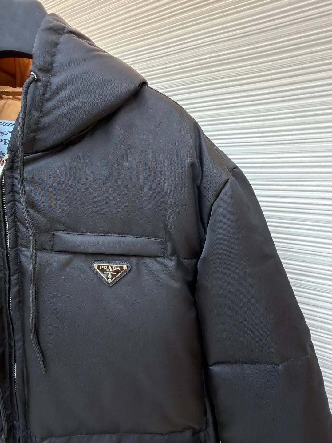 Prada Triangle Down Jacket ●Item No.: 1681316-C75 ●Fabric: White duck down fabric ●Technology: Mechanically filled with down ●Color: Black ●Version: Fitted version ●Weight: about 910 grams ●Size: S-M-L-XL ●Description: This down jacket is made of high-density water-repellent fabric, treated with a special coating, and has both windproof and anti-fouling properties. The hooded design is equipped with an adjustable drawstring, and the metal buckle at the end of the drawstring is customized by the brand, with fine texture and durability. The placket uses a two-way metal zipper with precise teeth, and the smoothness of the zipper has been tested for many rounds. The body of the garment is filled with high-quality goose down, which is evenly and plumply filled. The velvet is fixed through three-dimensional quilting technology to avoid velvet running while creating a layered silhouette. The brand triangle logo on the chest uses metal embossing + leather inlay technology, the edges are polished smooth, and the logo is three-dimensional and eye-catching. The pocket is a hidden zipper bag, and the zipper is the same color as the fabric, which is both practical and beautiful. The cuffs use micro-elastic edge processing to fit the wrist without restricting movement. The overall tailoring follows an oversize version, and seamless gluing technology is used at the splicing points to reduce thread exposure and improve wearing comfort and sophistication of garments. Every craftsmanship demonstrates Prada's strict standards for high-end clothing. The overall wiring is straight and delicate, the fabric is comfortable and soft, and the color is consistent without color difference. It can be matched with the same style to create a fashionable look and control various occasions. Customized accessories, complete with three standards, same style for men and women!