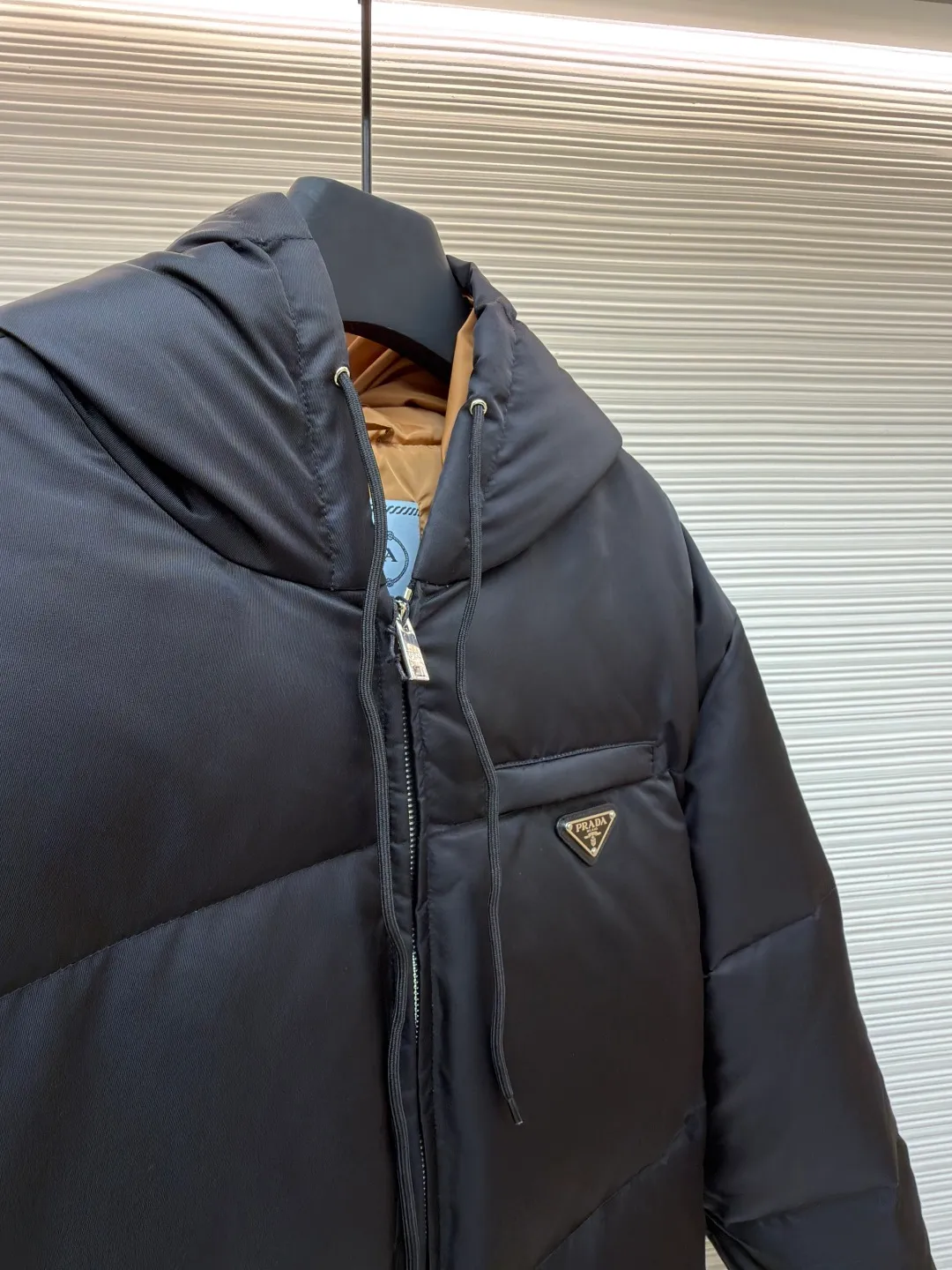 Prada Triangle Down Jacket ●Item No.: 1681316-C75 ●Fabric: White duck down fabric ●Technology: Mechanically filled with down ●Color: Black ●Version: Fitted version ●Weight: about 910 grams ●Size: S-M-L-XL ●Description: This down jacket is made of high-density water-repellent fabric, treated with a special coating, and has both windproof and anti-fouling properties. The hooded design is equipped with an adjustable drawstring, and the metal buckle at the end of the drawstring is customized by the brand, with fine texture and durability. The placket uses a two-way metal zipper with precise teeth, and the smoothness of the zipper has been tested for many rounds. The body of the garment is filled with high-quality goose down, which is evenly and plumply filled. The velvet is fixed through three-dimensional quilting technology to avoid velvet running while creating a layered silhouette. The brand triangle logo on the chest uses metal embossing + leather inlay technology, the edges are polished smooth, and the logo is three-dimensional and eye-catching. The pocket is a hidden zipper bag, and the zipper is the same color as the fabric, which is both practical and beautiful. The cuffs use micro-elastic edge processing to fit the wrist without restricting movement. The overall tailoring follows an oversize version, and seamless gluing technology is used at the splicing points to reduce thread exposure and improve wearing comfort and sophistication of garments. Every craftsmanship demonstrates Prada's strict standards for high-end clothing. The overall wiring is straight and delicate, the fabric is comfortable and soft, and the color is consistent without color difference. It can be matched with the same style to create a fashionable look and control various occasions. Customized accessories, complete with three standards, same style for men and women!