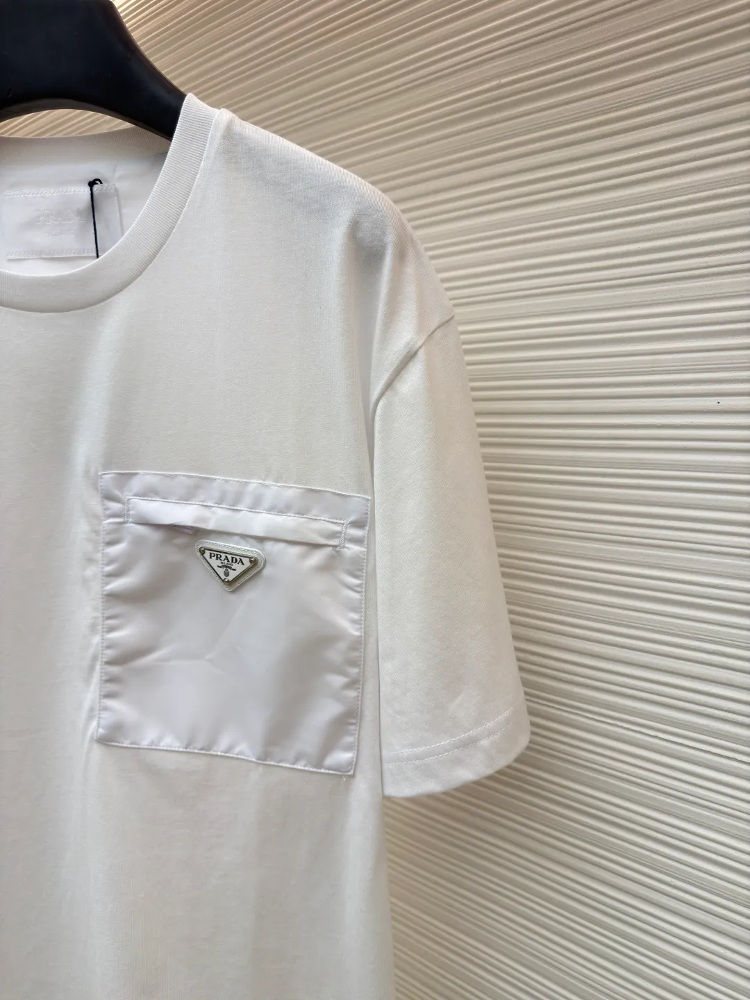 Prada Triangle Logo Pocket Short Sleeves ●Original version: Purchased and developed for 7000 ●Item number: 1682395-A05 ●Fabric: High-elastic jersey fabric ●Technology: Needle and shuttle splicing ●Color: white ●Version: Fitted version ●Weight: about 230 grams ●Size: S-M-L-XL ●Description: Customized high-elastic jersey material, delicate and soft, comfortable and close to the skin, a touch of simple white, as pure as ever, elegant and self-evident The iconic Prada triangle logo is embellished on the chest. It is integrated with Re-Nylon nylon fabric to decorate the square silhouette. Cross-disciplinary aesthetic grafting. The exquisite small pocket design highlights quality and style. It reveals a flexible and relaxed beauty. It is a picture of strolling in the city and deconstructs the attitude of the modern gentleman. The infrared positioning of the "Prada triangle mark" by an imported special machine is more precise and firm. Needle and shuttle stitching technology can make full use of the respective advantages of knitted fabrics and woven fabrics. By choosing the appropriate sewing process and stitches, it can ensure that the splicing parts are strong and beautiful. Template machine bag opening The preset template guides the position, shape and size of the bag opening. The accuracy ensures the quality of the bag opening effect. The overall wiring is straight and delicate, the fabric is comfortable and soft, and the color is consistent without color difference. It can be matched with the same style to create a fashionable look and control various occasions. Customized accessories, complete with three standards, same style for men and women!