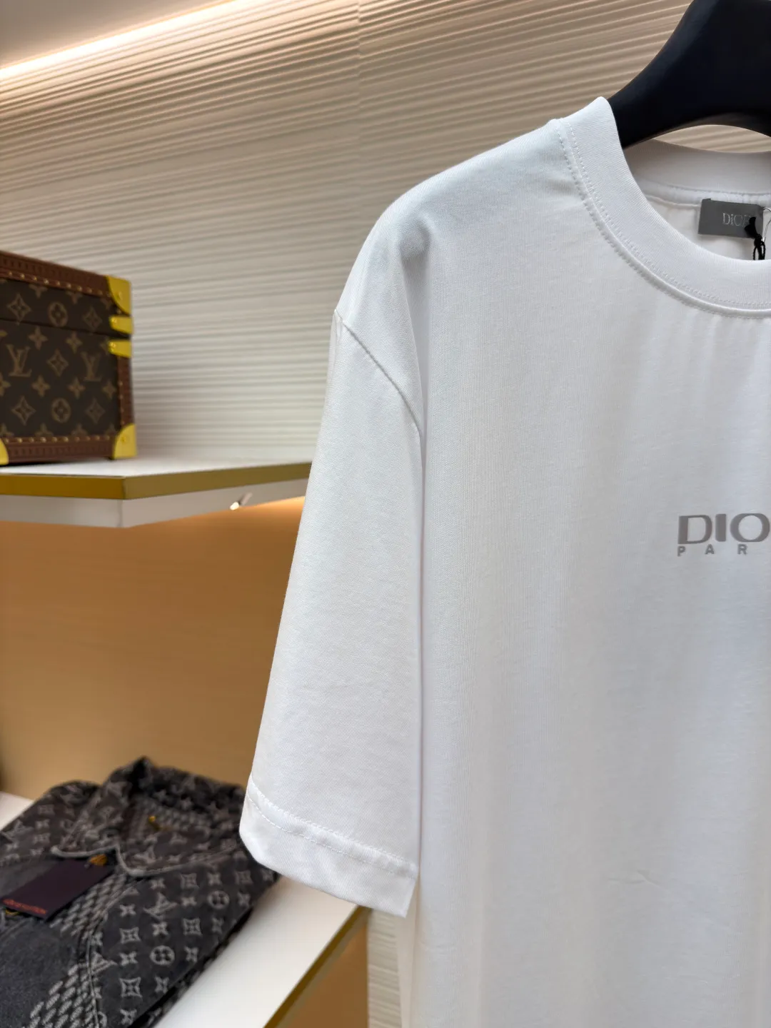 Dior Reflective Triangle Icon Round Neck Short Sleeve ●Item No.: 1681100-A00 ●Fabric: Jersey fabric ●Technology: Reflective lettering and embossed production ●Version: Fitted version ●Weight: about 205 grams ●Size: S-M-L-XL ●Description: The main body is made of 24S special woven compact cotton to make jersey fabric, weight 180g. High-count combed cotton yarn eliminates most of the short hairiness through compact spinning process, making the yarn smoother and stronger. The woven fabric structure is extremely dense, flat and soft, with excellent anti-pilling ability and durability, while retaining the natural advantages of pure cotton, which is breathable and skin-friendly. The neckline is made of 32S 1x1 rib with a weight of 300g. The finer yarn count creates a more delicate and tight thread, which provides better elasticity and deformation resistance than ordinary ribs, ensuring that the neckline can still remain stiff after being put on and taken off many times. The reflective engraving and embossing process is a sophisticated technology that combines safety functions with visual aesthetics. The core is to use a reflective lettering film with a built-in micro-glass bead layer. First, a high-precision laser cutting machine is used to engrave the outline according to the designed fonts and patterns to ensure that the edges are clear and burr-free. The cut reflective film is accurately attached to the surface of the fabric through heat transfer printing equipment under specific temperature and pressure, so that it is firmly combined with the fabric fibers. The case is matte silver-gray under normal conditions, but when illuminated by light, the micro-glass bead layer can achieve efficient retroreflection and instantly present a striking bright effect. The finished product is washable and abrasion resistant, perfectly meeting the dual needs of sportswear for functionality and visual tension. The overall wiring is straight and delicate, the fabric is comfortable and soft, and the color is consistent without color difference. It can be matched with the same style to create a fashionable look and control various occasions. Customized accessories, complete with three standards, same style for men and women!