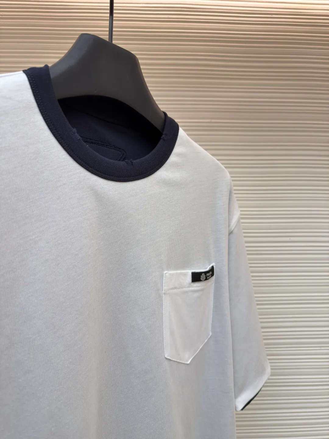 Prada double-sided design logo short sleeves ●Original version: Purchased and developed at 9150 ●Item number: 1682527-A15 ●Material: Velvet-feel plain cotton fabric ●Technology: Precision splicing and seaming production ●Color: Navy blue ●Version: Fitted version ●Weight: about 330 grams ●Size: S-M-L-XL ●Description: Customized velvet-feel plain cotton, soft and delicate, comfortable and close to the skin, twin aesthetics of gray and white interweaving Wearing the minimalist philosophy of two souls, the cloud white on the front uses Prada label details to define high-end restraint. The contrasting rib collar locks all eyes. The high-grade gray on the back uses the back triangle to highlight the essence of the brand. It is a quiet but unignorable presence. Combined with the frayed design, it is sublimated, filled with artistic atmosphere, double-sided elegance, and leads the trend. Precise splicing and seaming technology uses advanced sewing technology and equipment to ensure that the splicing of each short sleeve is smooth and tight, with smooth lines, and there will be no gaps inside and outside. The neckline is sewn using a computerized double-needle sewing process, using an advanced control system to sew two parallel stitches at the same time. Ensure that the size and shape of the neckline remain consistent, and use positioning and manual fraying. Local friction and wear on the fabric through manual operation will cause a natural damage effect on the surface of the fabric. The overall wiring is straight and delicate, the fabric is comfortable and soft, and the color is consistent without color difference. It can be matched with the same style to create a fashionable look and control various occasions. Customized accessories, complete with three standards, same style for men and women!
