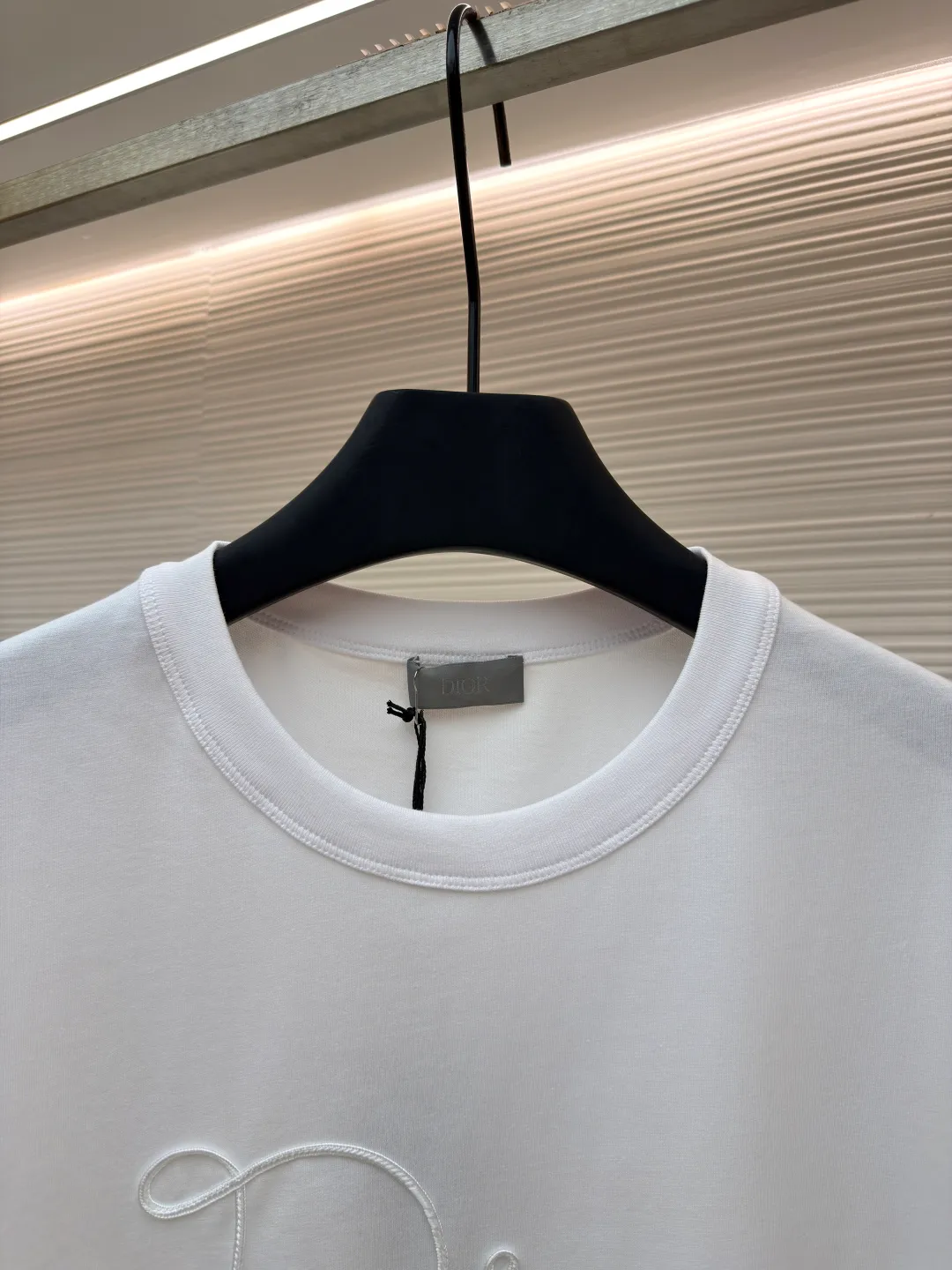 Dior satin emblem round neck short sleeves ●Original version: purchased and developed by 7089 ●Item number: 1681695-A00 ●Fabric: cotton jersey fabric ●Technology: embroidery production ●Color: white ●Version: fitted version ●Weight: about 205 grams ●Size: XS-S-M-L ●Description: The main body is made of 24-count special-spun compact cotton. The weight of 185g/㎡ is light to medium, ensuring the lightness, breathability and good drape of the T-shirt. It is suitable for both spring wear alone and as an inner layer. With 32 pieces of 1×1 rib, 300g/㎡. Its special spinning and compacting process means that compact spinning technology is used in the spinning process, which effectively reduces the hairiness of the yarn, making the yarn smoother and stronger. The woven fabric therefore has the advantages of compact structure, smooth surface, and resistance to pilling. The final dark gray tone is combined with the simple texture of jersey to create a high-end matte texture. Embroidery decoration in the form of satin ribbons, which are fixed on the fabric through special processing. The texture brought by this process is usually different from the woven texture and slight luster of the main knitted fabric. It forms a delicate and accessible visual and tactile focus on the matte dark gray base, enhancing the craftsmanship, design and uniqueness of the single product. The overall wiring is straight and delicate, the fabric is comfortable and soft, and the color is consistent without color difference. It can be matched with the same style to create a fashionable look and control various occasions. Customized accessories, complete with three standards, same style for men and women!